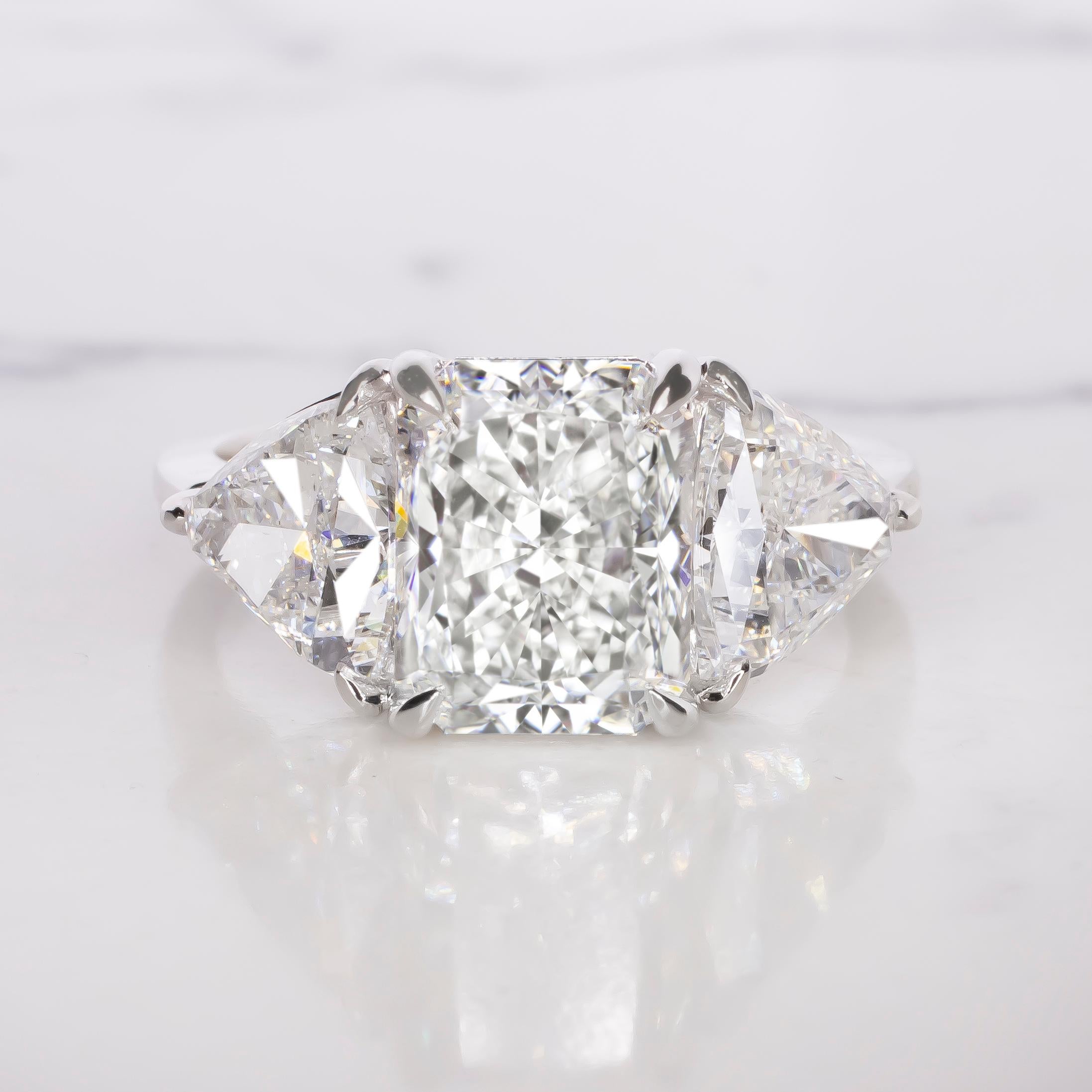 This breathtaking engagement ring features a 3.01 carat radiant cut diamond as the focal point, set in lustrous 18K white gold. 

The diamond’s color grade E gives it a stunningly bright and icy appearance, exuding timeless elegance. 
With minute