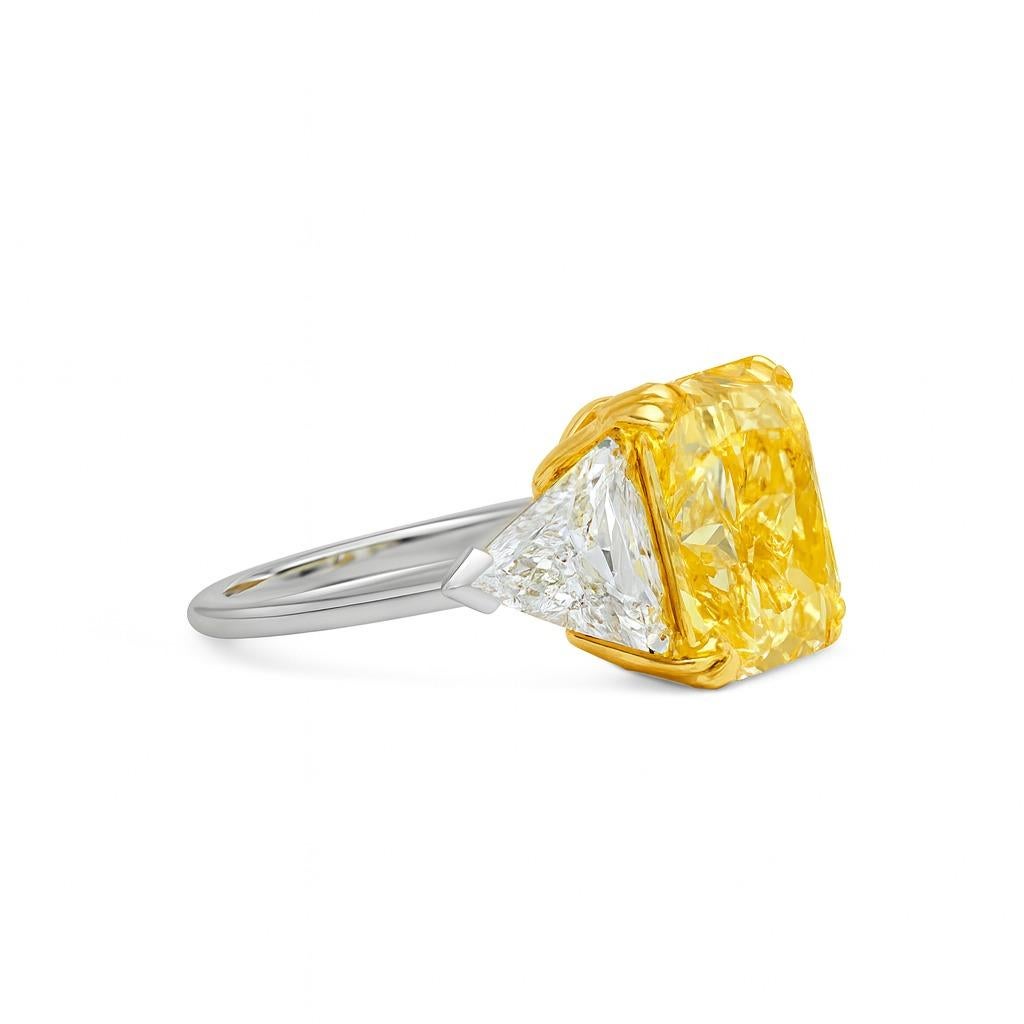 This striking three stone engagement ring presents a 3 carat radiant cut diamond set in a refined two-tone design. Crafted in 18K white gold with the upper head in 18K yellow gold, the setting enhances the intense vibrancy of the center stone. Two