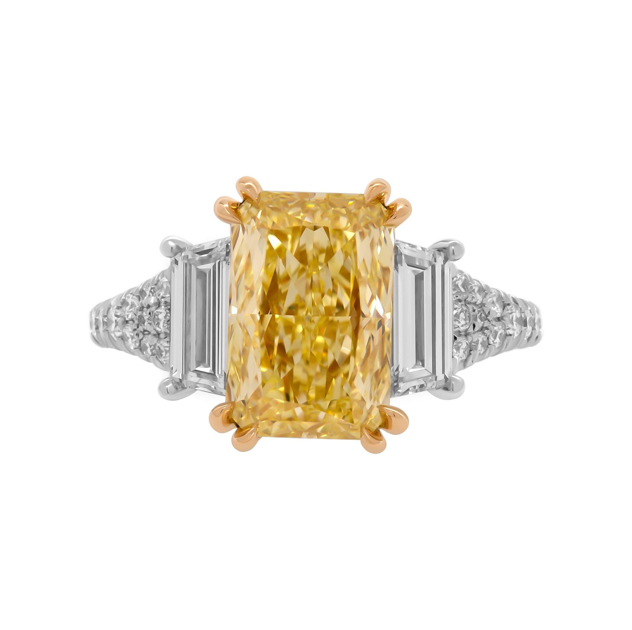3 stone ring in Platinum & 18K Yellow Gold
Center: 3.34ct Natural Fancy Yellow Even VVS2 Radiant Shape Diamond GIA#2225384189 
Side stones: Two side stones: 0.93ct E color VVS clarity trapezoids 
Cathedral diamond shank; diamond center wire
Total