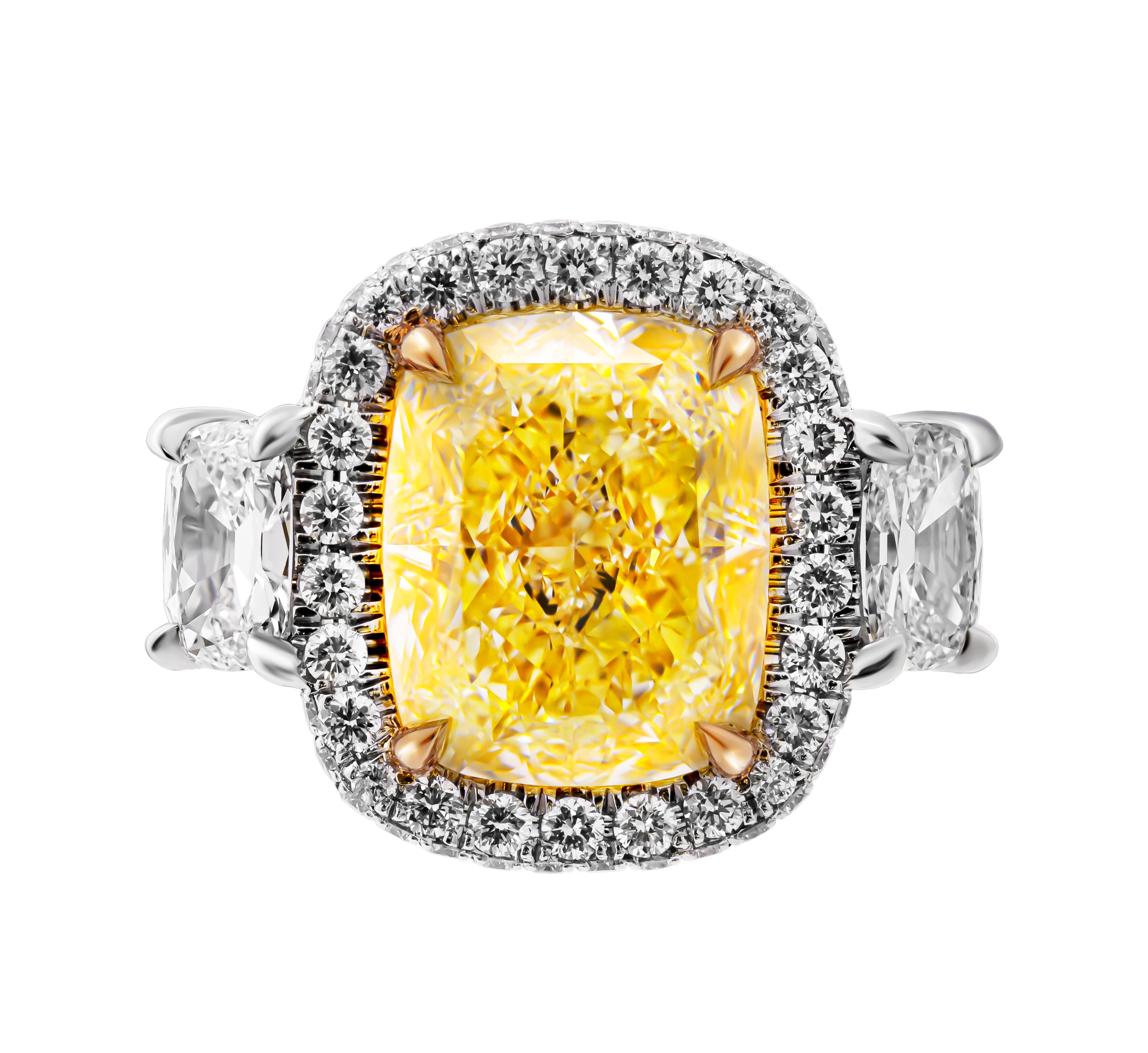 Immerse yourself in the elegance and sophistication of this GIA certified three-stone ring, masterfully crafted in a blend of 18k yellow gold and platinum. This stunning piece features a magnificent 6.31-carat natural fancy light yellow cushion-cut