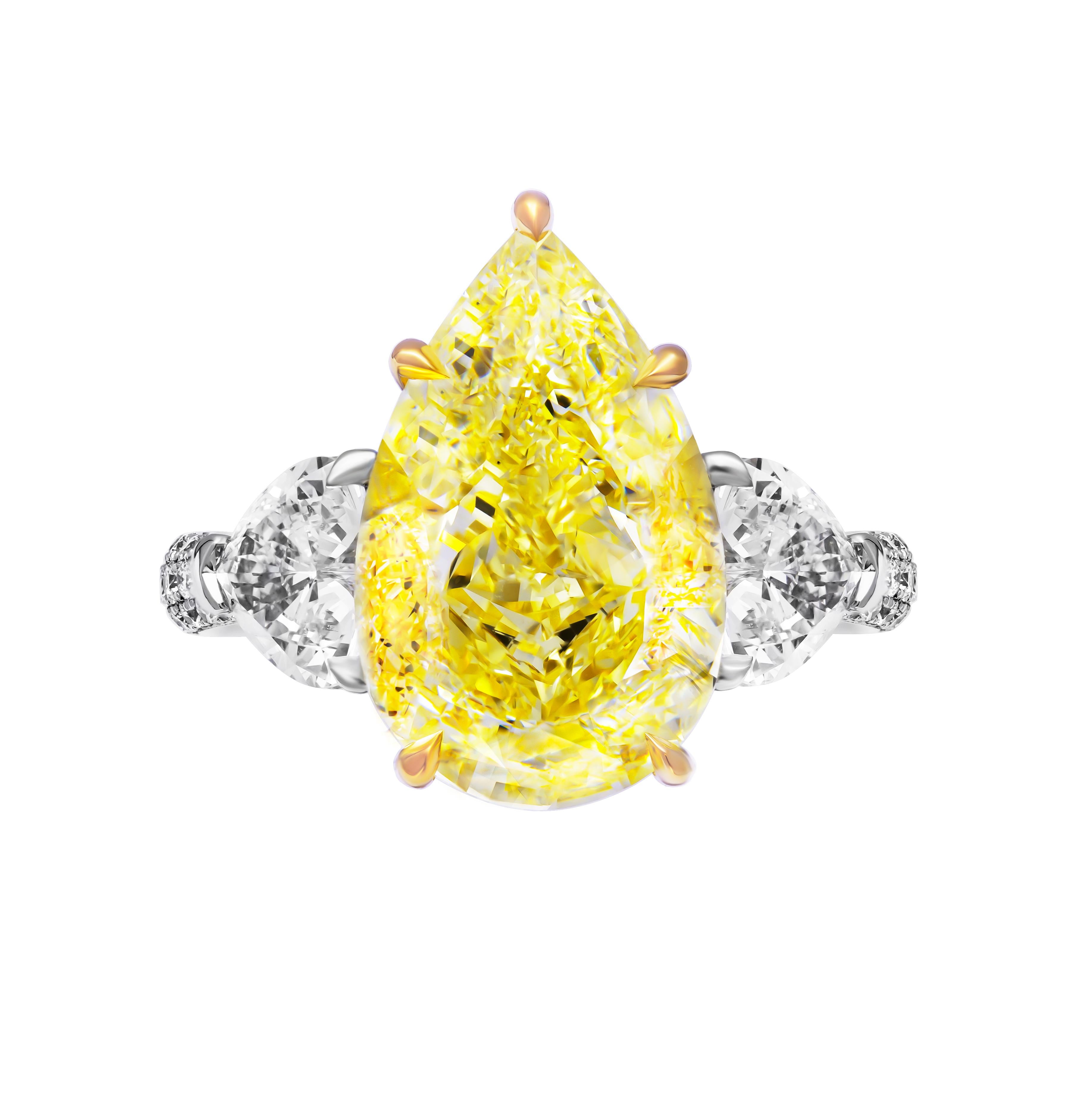 Immerse yourself in the splendor of luxury with this extraordinary three-stone ring, meticulously crafted in a harmonious blend of 18K yellow gold and 950 platinum. At its focal point reigns a magnificent 7.78-carat fancy yellow pear-shaped diamond,