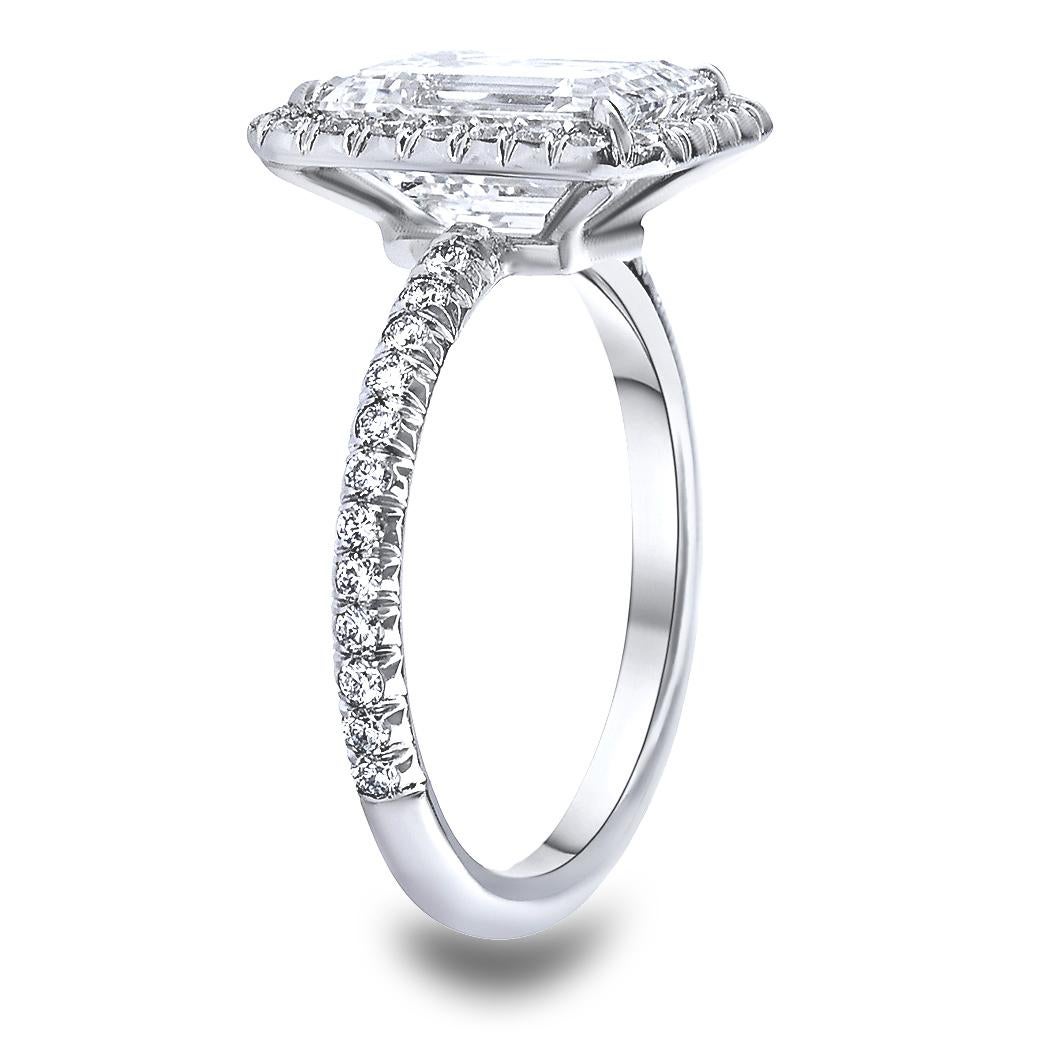 Stunning custom made engagement ring. Crafted in hand made platinum mounting set with a 3.01 CT Emerald Cut Diamond, F Color, and super eye clean SI1 Clarity. Diamond appears much larger than its actual size, with a diamond halo and diamond