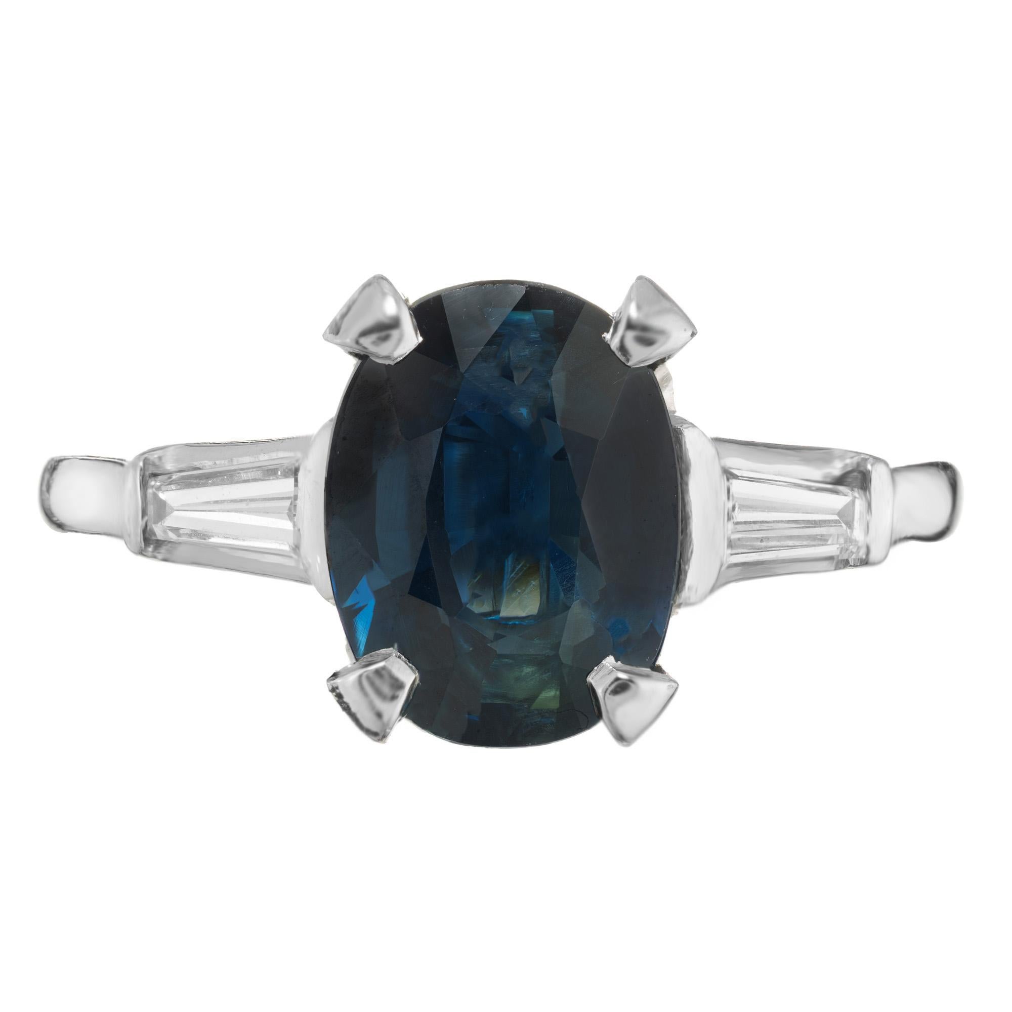 Vintage 1950's three-stone sapphire and diamond engagement ring. Mounted with a 3.01ct oval deep blue sapphire center stone. Accented by a tapered baguette diamond on each side. The sapphire is certified by the GIA natural, no heat. The stunning