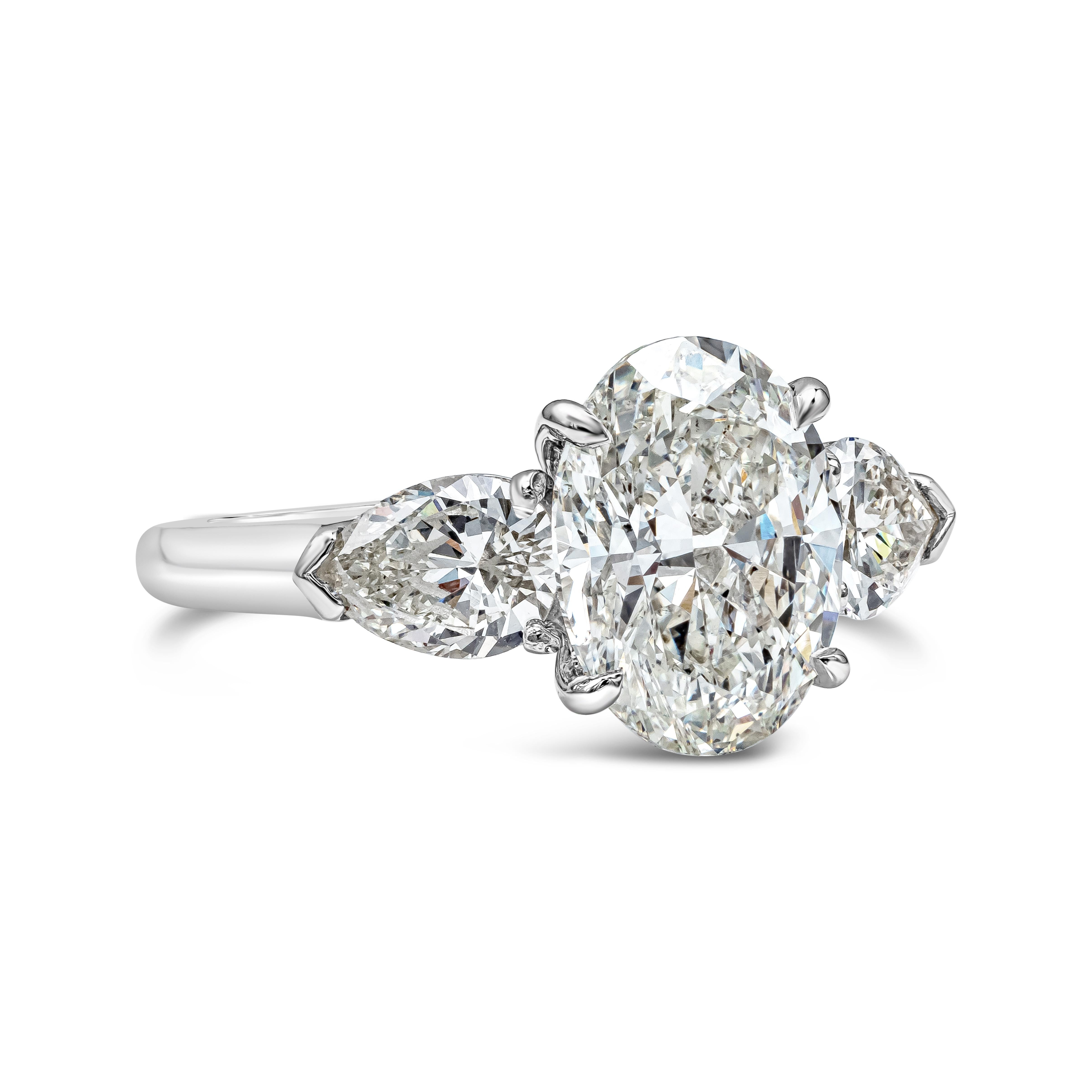  A classic three-stone engagement ring showcasing a 3.02 carat oval cut diamond certified by GIA as J color, SI1 clarity, flanked by pear shape diamonds on either side. Accent diamonds weigh 1.01 carats and are approximately J color, VS clarity. Set