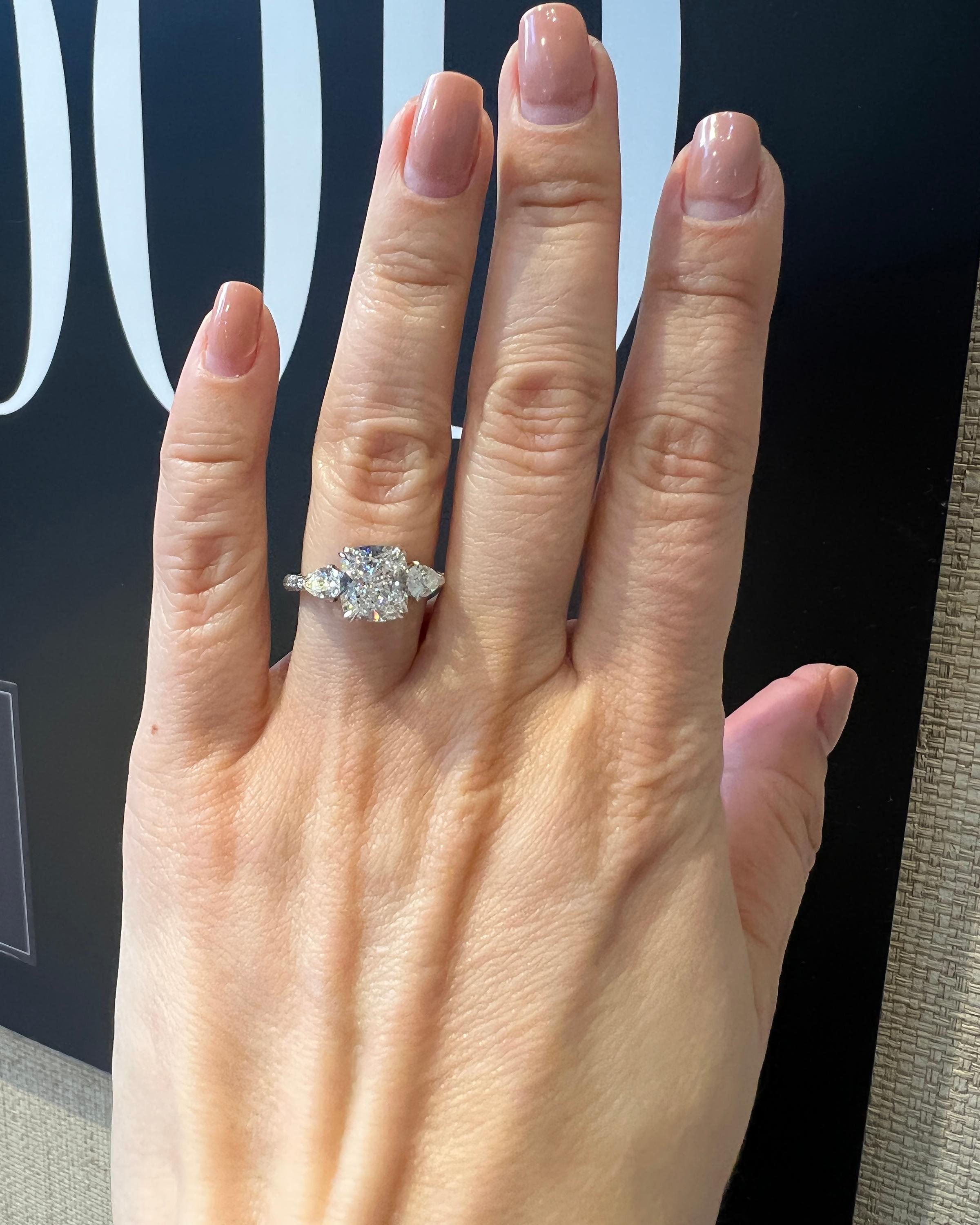 An engagement ring comprising of a center cushion diamond and two side pear shape diamonds. Pave diamonds half way on the band, by Spectra Fine Jewelry.
The center stone is accompanied by a GIA report stating that it's H color, VS1 clarity.
Metal is