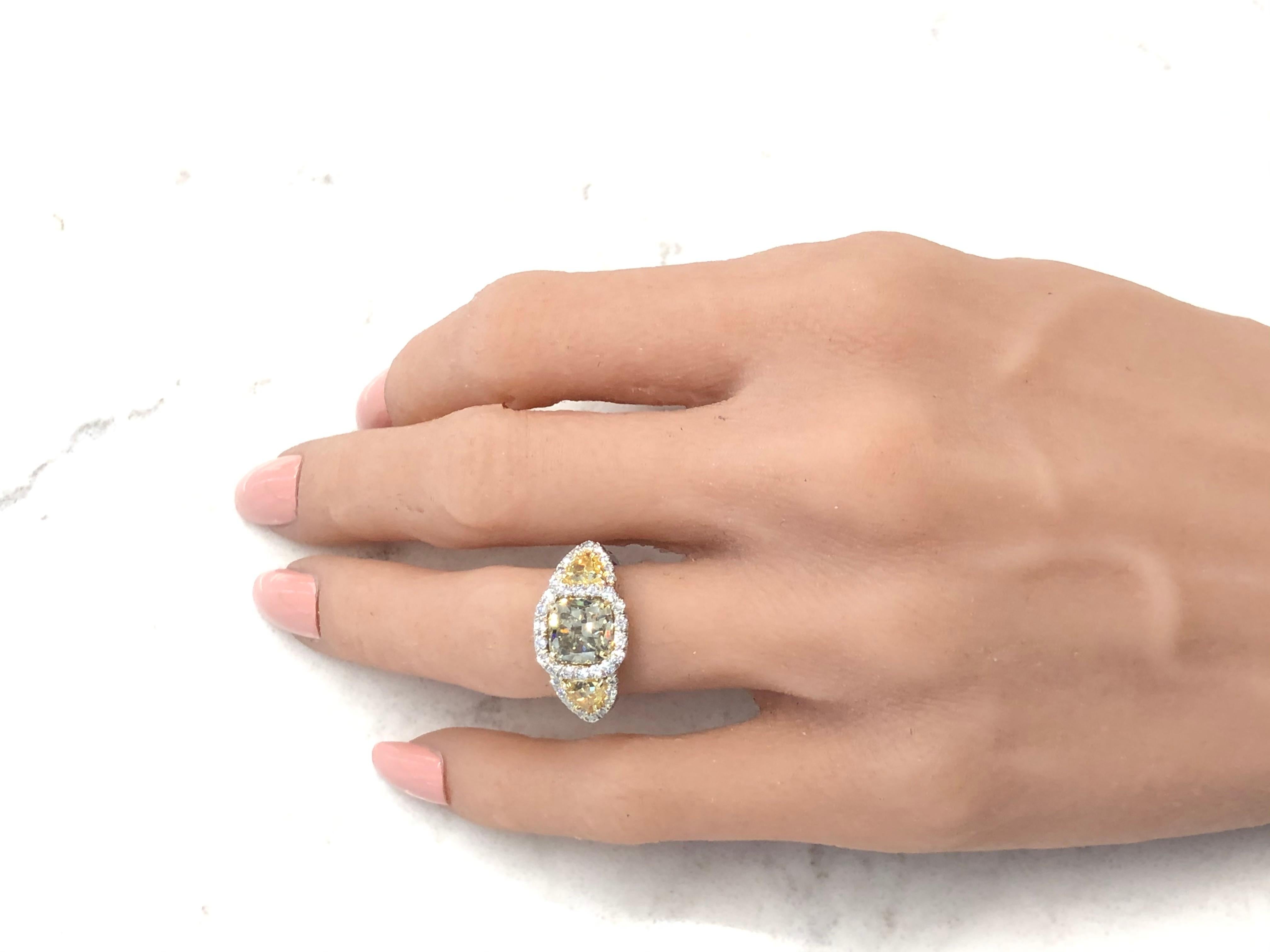 Celebrate your birthday or anniversary occasion in ultimate style with this show-stopping multi-diamond ring made in brightly polished platinum. A 3.10-carat cushion cut fancy brownish-greenish yellow diamond takes center stage with SI2 clarity,