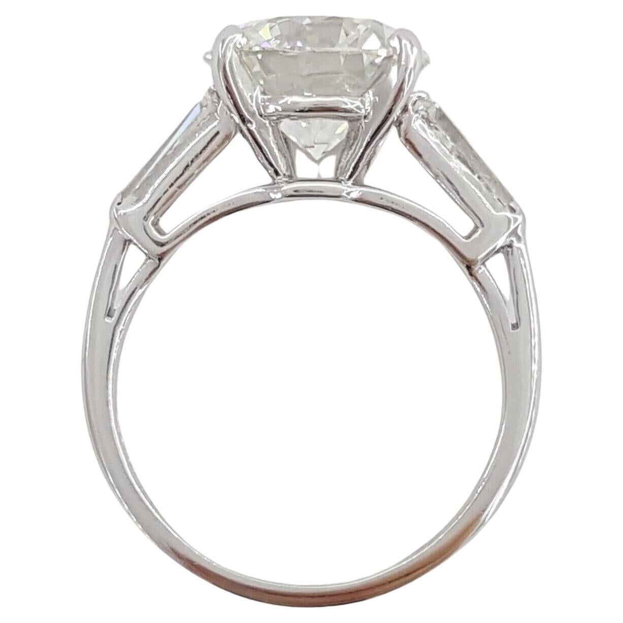 This exquisite GIA certified ring features a stunning 3.01 carat round cut diamond, brilliantly set in luxurious platinum. 
Complementing the central stone are two tapered baguette diamonds, which enhance the overall elegance and sophistication of