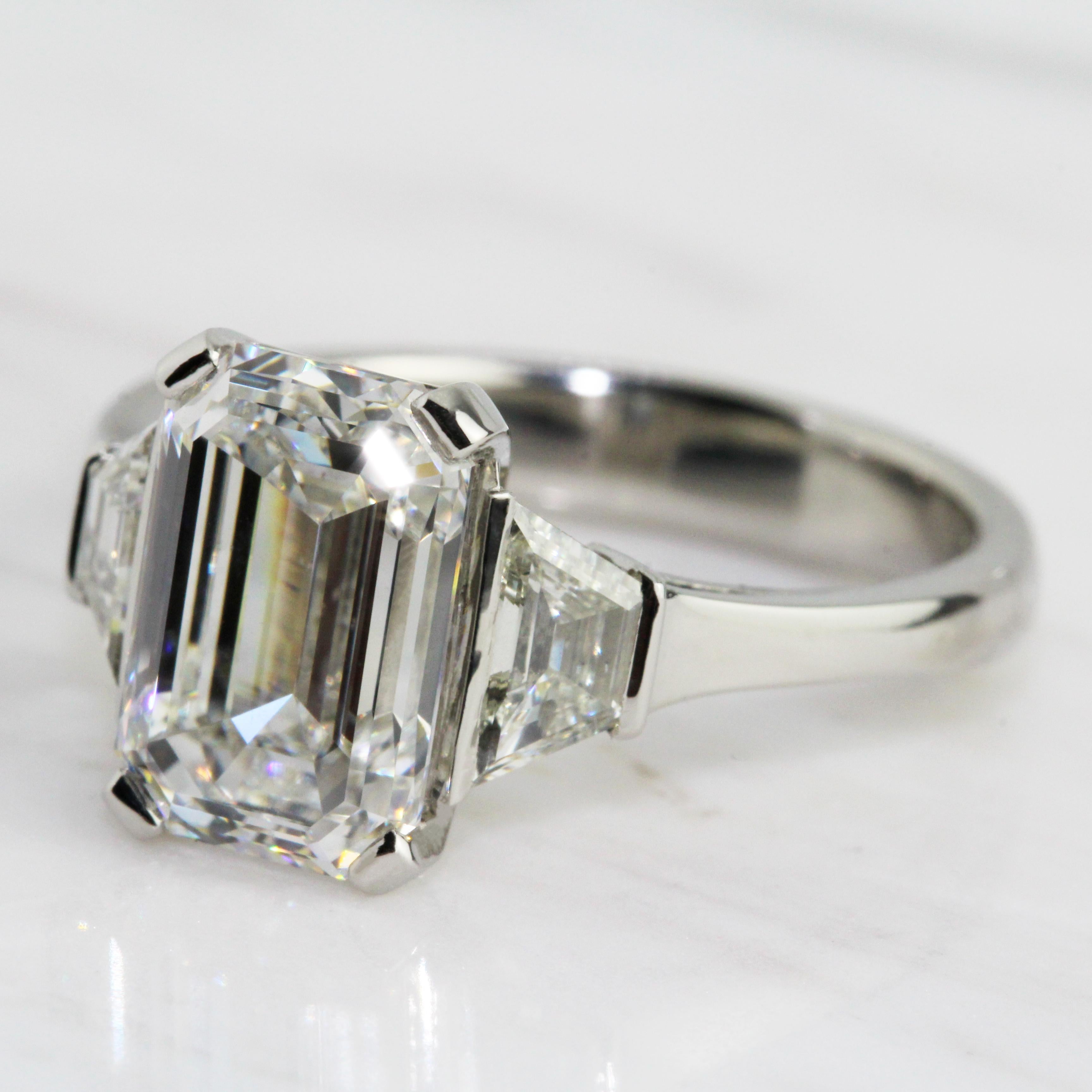 A magnificent diamond ring by Ronan Campbell, words do not do this piece justice, it is a piece which has to be tried on to fully appreciate. A breathtaking emerald cut diamond (3.15ct E Colour SI1 Clarity GIA) is matched perfectly by two custom cut