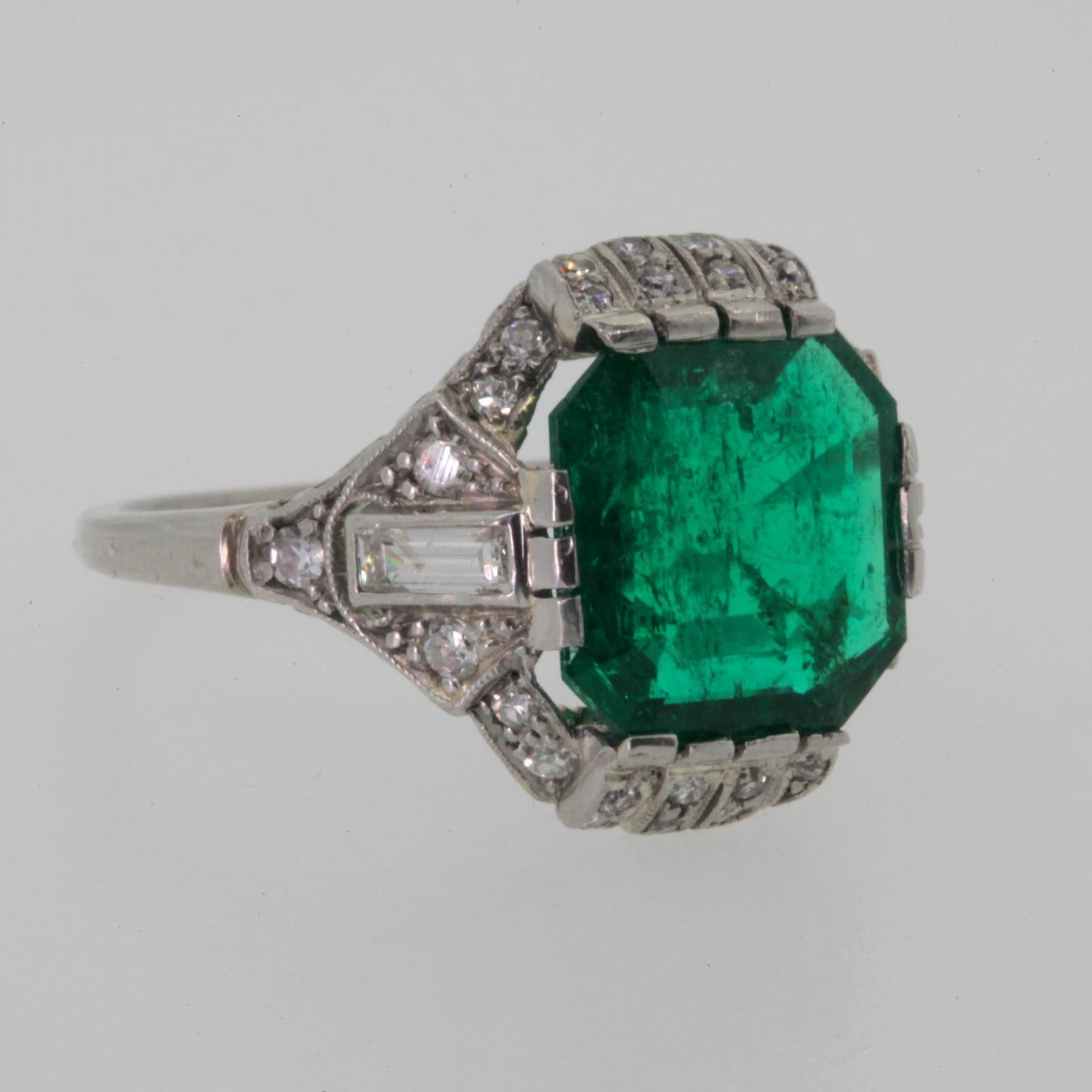 This stunning 1930s platinum ring features a gorgeous deep green cut corner 3.18 carats Emerald, accompanied by  G.I.A. report #5192177719 stating that the Emerald is of Colombian origin.  The lovely Art Deco setting with open swirl gallery shows