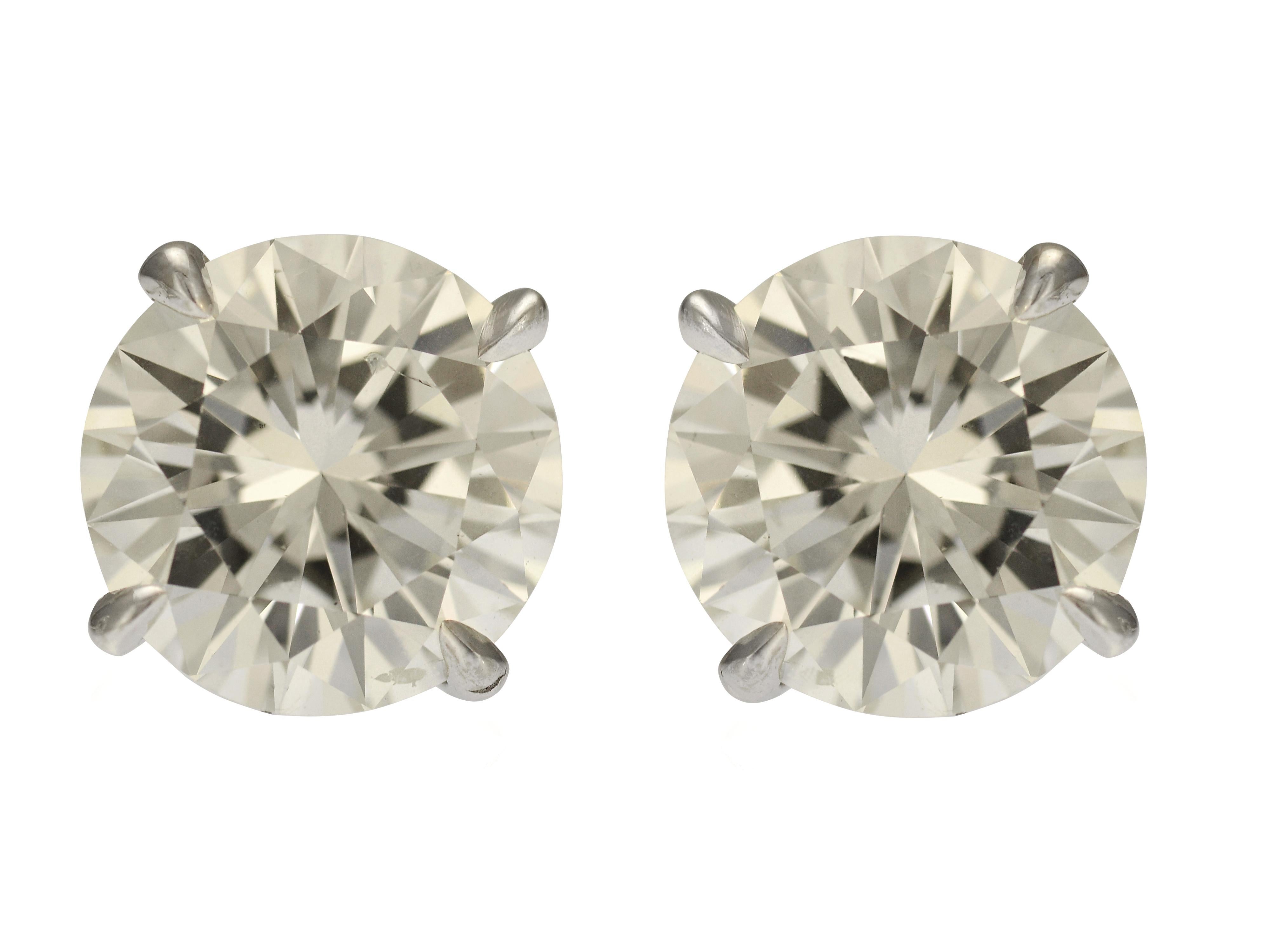 This pair of matched diamond stud earrings are crafted in 14 karat white gold with 4 prong baskets. The 2 round brilliant cut GIA graded diamonds are 1.57 carat SI1 clarity with G color, and 1.62 carat SI2 clarity with H color respectively, with a