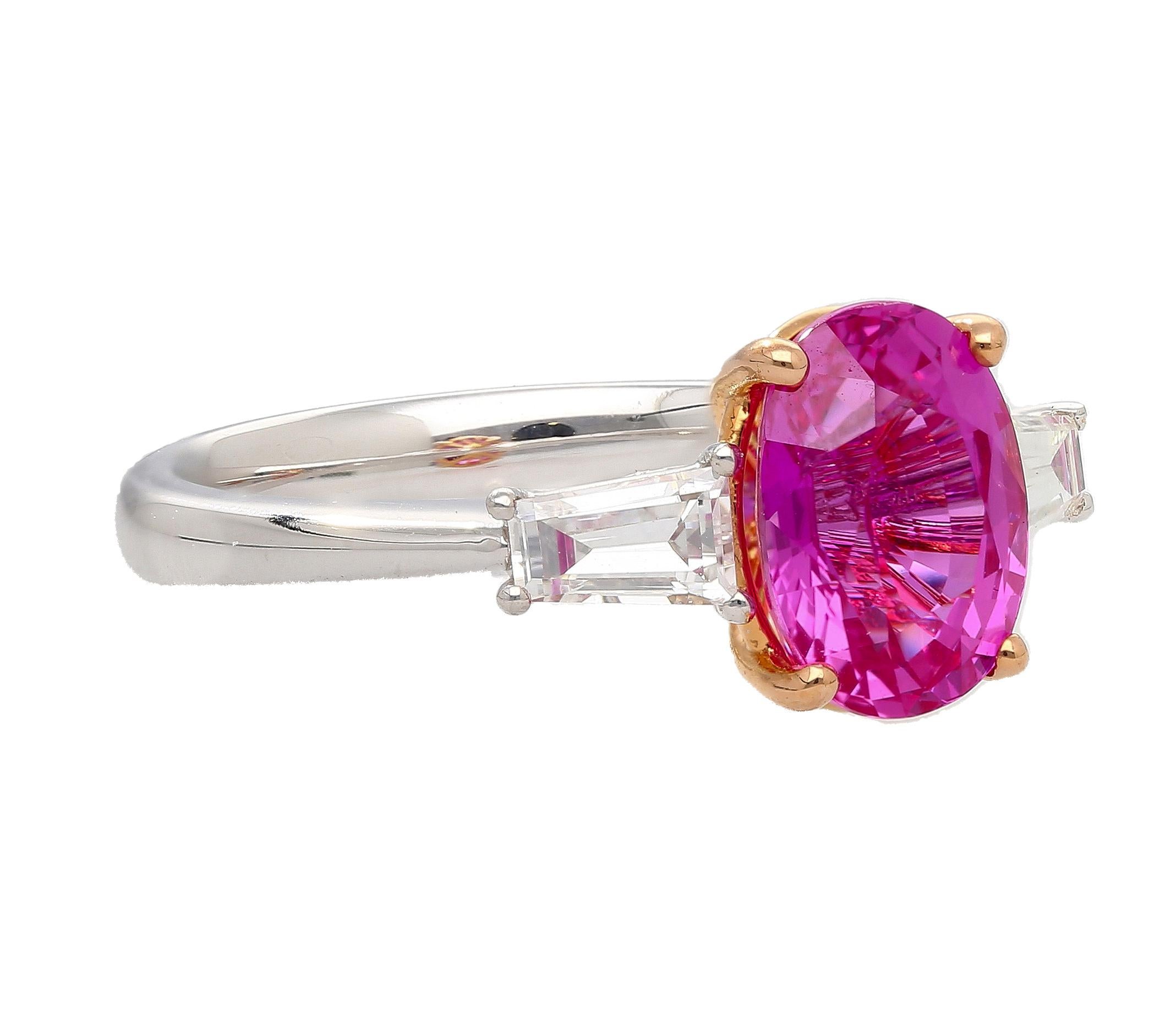 Dieser Ring aus 18 Karat Weißgold ist mit einem GIA-zertifizierten 3,2-karätigen rosa Saphir mit Ovalschliff aus Madgaskar besetzt. Dieser lebhafte Edelstein ist in einer 4-Zacken-Fassung gefasst und von 2 Diamanten im Baguetteschliff mit einem