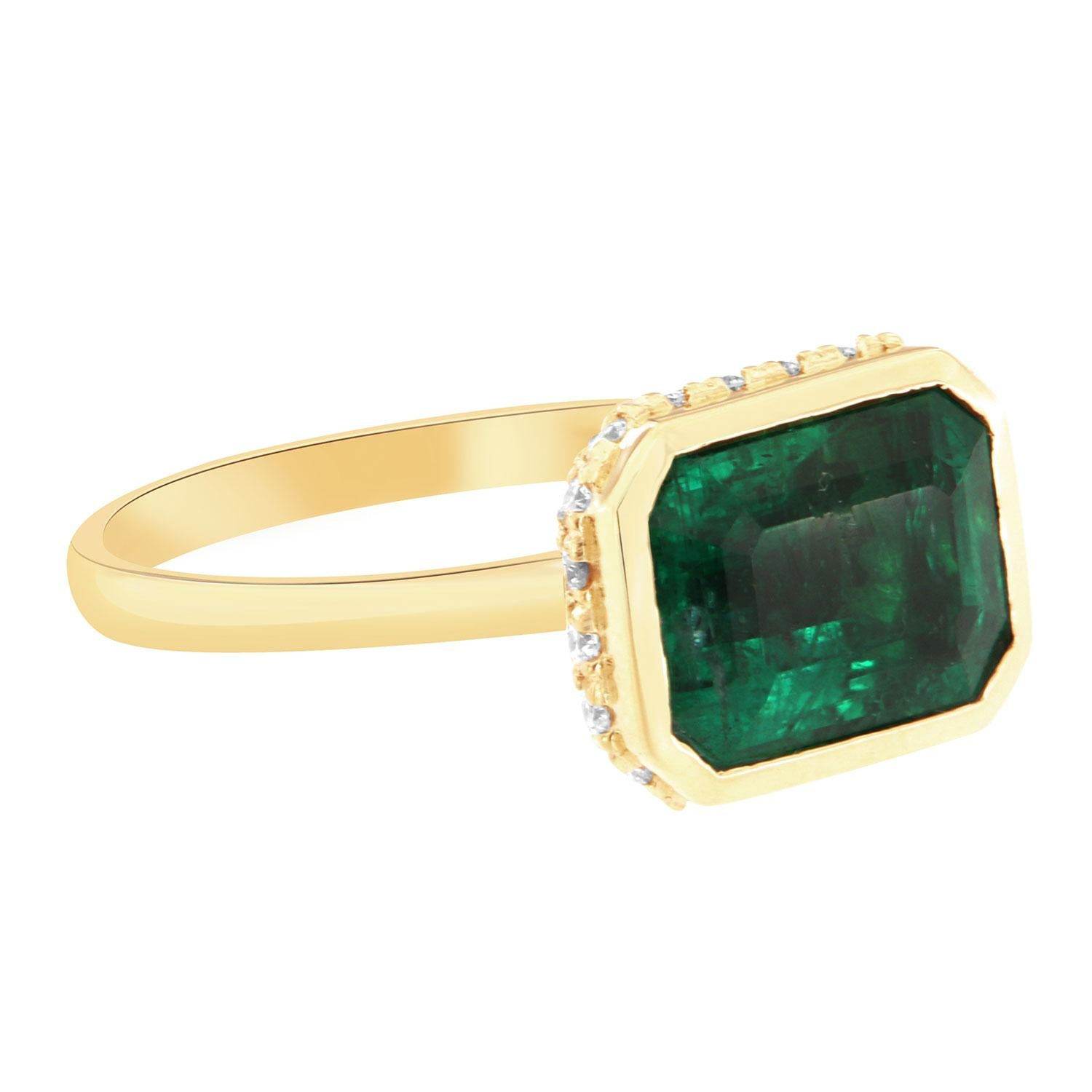 This beautiful 18K yellow gold ring features a GIA-certified 3.23 Carat Emerald-shaped Green Emerald bezel set.  A hidden halo of brilliant round diamonds encircled the crown on top of a 2.00 mm wide band. 
The diamonds total weight is 0.32