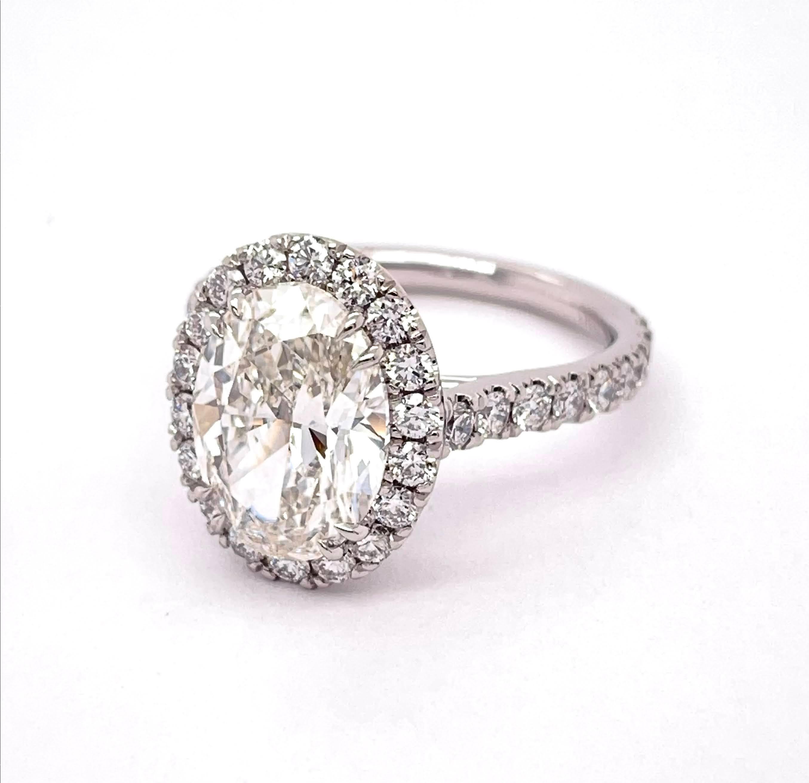 GIA Certified Oval Shape Cut Diamond 3.30, H Color VVS1 Clarity, and wrapped elegantly with 1.11 carats fine round diamonds from the halo down to its shank on a Platinum setting. Made to perfection with the highest quality.

