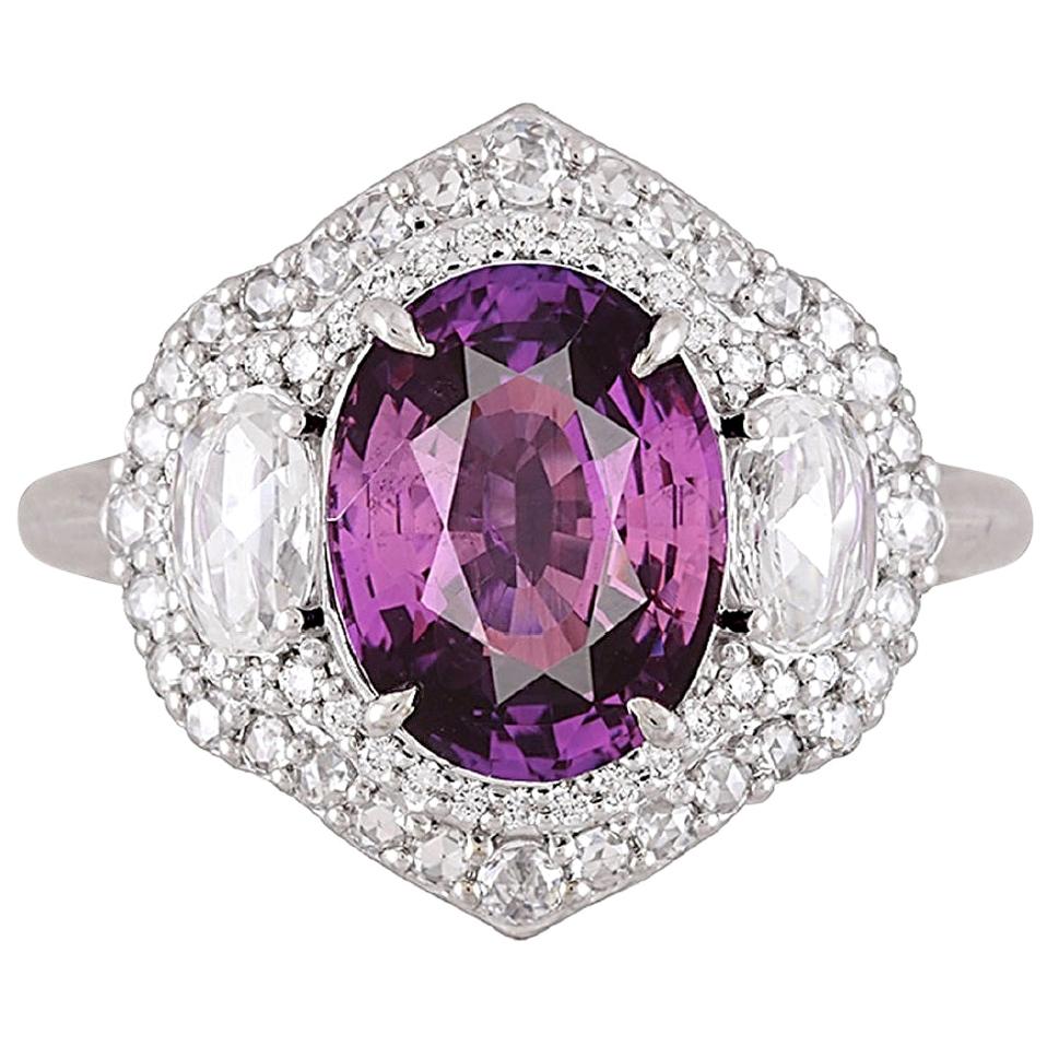 Featuring a GIA Certified 3.31 carat oval-cut purple sapphire at its center, accompanied by two oval-shaped white diamonds, this ring radiates brilliance from every perspective. The trio of center stones is gracefully encircled by a double halo of