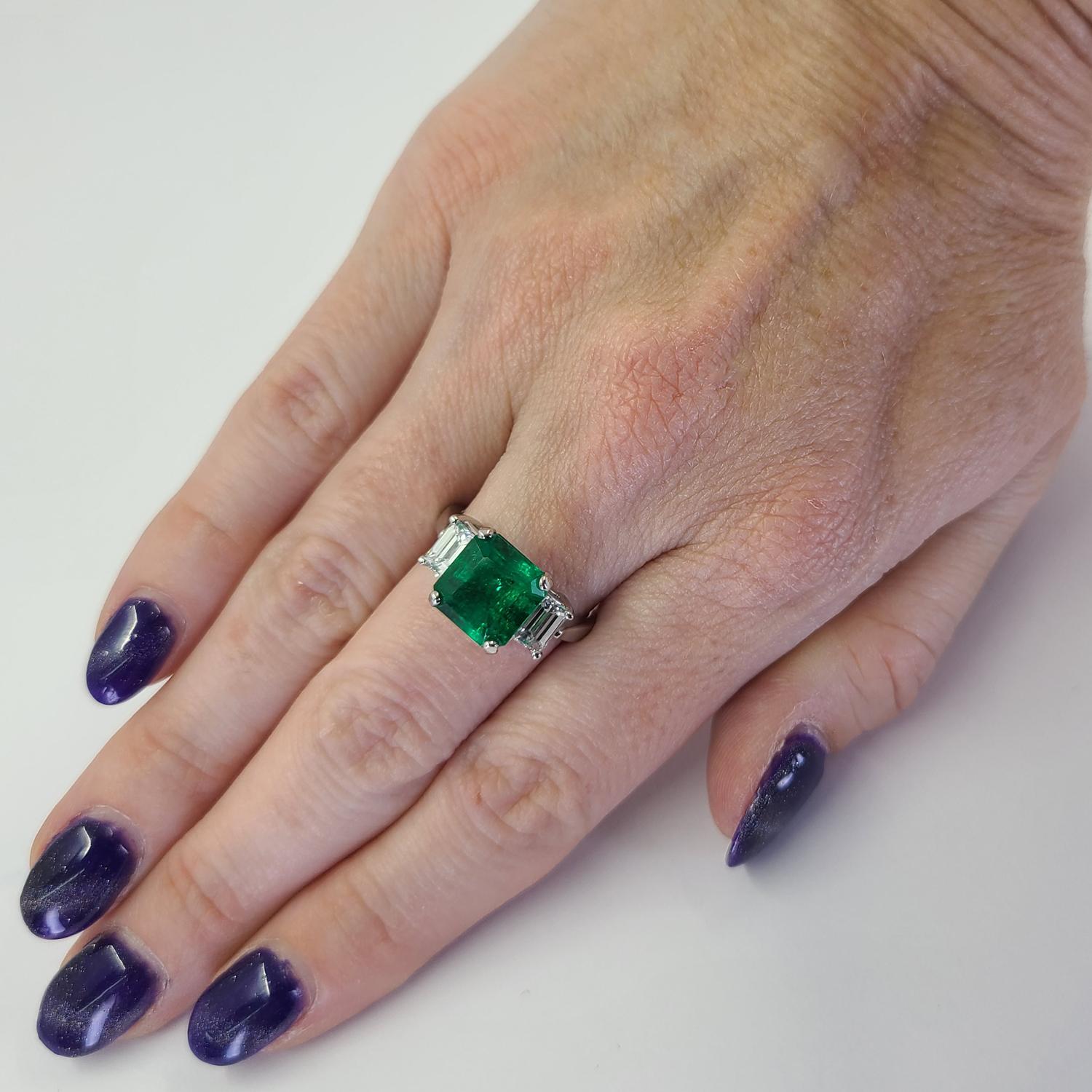 Stunning Platinum 3 Stone Ring Featuring A 3.38 Carat Emerald Cut Colombian Emerald (GIA Report #5222713474) Accented By 2 Emerald Cut Diamonds of VS Clarity and G Color Totaling Approximately 1.00 Carat. Finger Size 6.5; Purchase Includes One