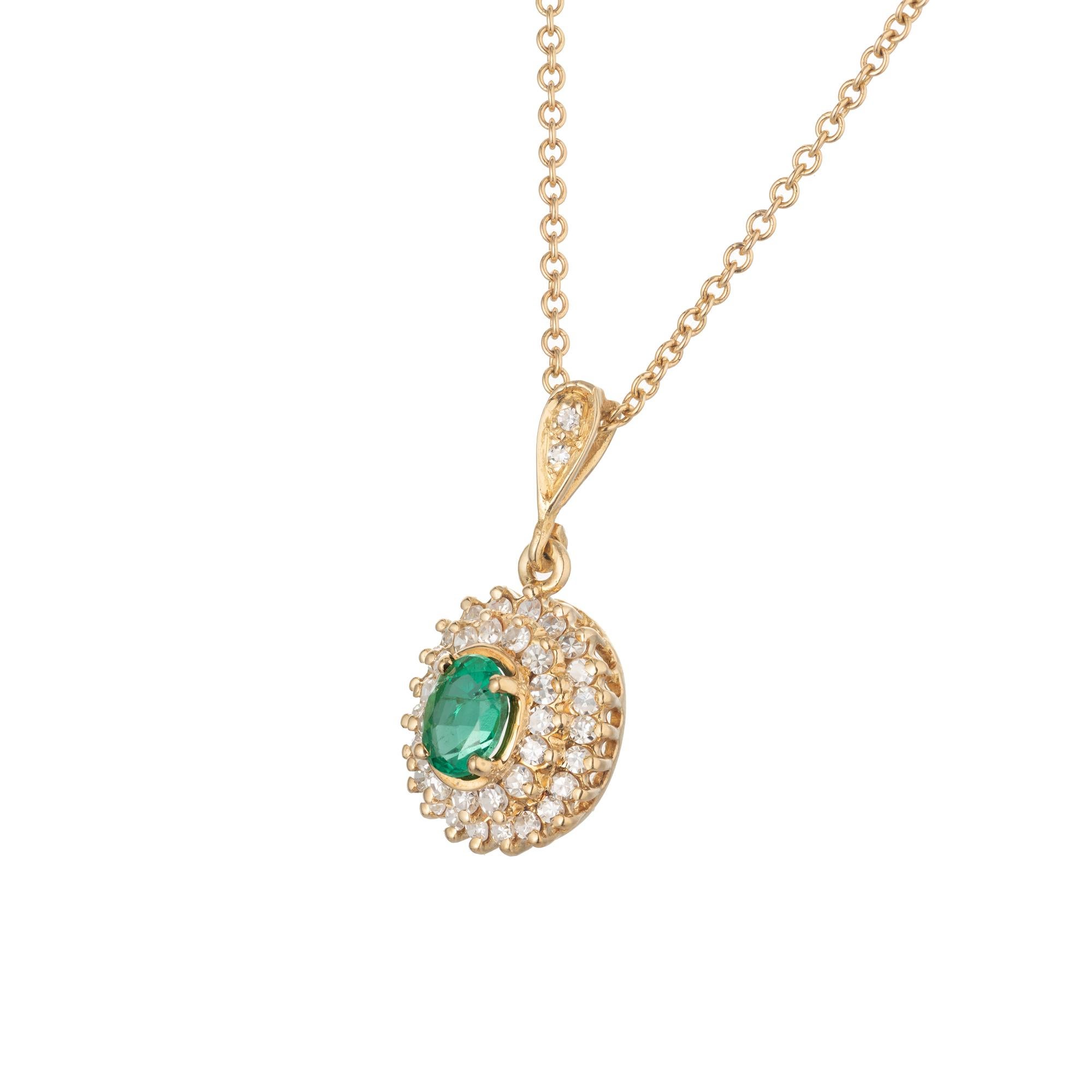 Emerald diamond pendant necklace circa 1950-1960 with a bright green GIA certified natural center emerald with a two row halo of round diamonds in a tiered design. 18k yellow gold chain. 18 inches. 

1 oval green MI emerald, Approximate .35ct GIA