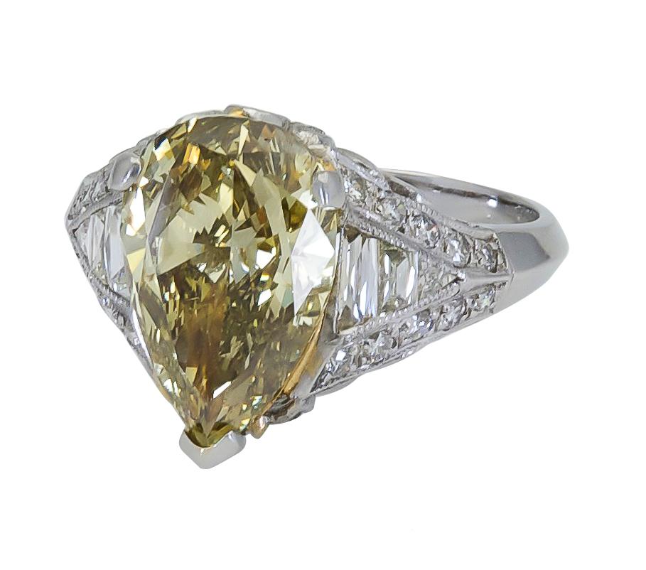 Engagement ring featuring a 3.51 carat pear shape yellow diamond certified by GIA as Fancy Dark Gray-Greenish Yellow, set in an in art deco style mounting made in platinum. Mounting is accented with brilliant and step-cut diamonds weighing 0.65