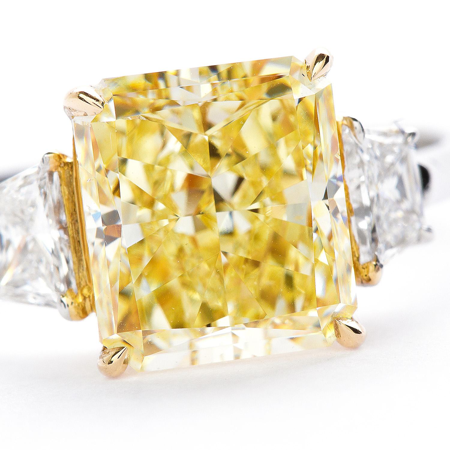 Striking three stone ring. Featuring a GIA Certified 3.52 Carat, Fancy yellow Radiant Cut Diamond, VS2 clarity. The stunning sunshine color like center stone is set in handmade platinum and Yellow Gold. Flanked by two trapezoid stones approx. 1.30