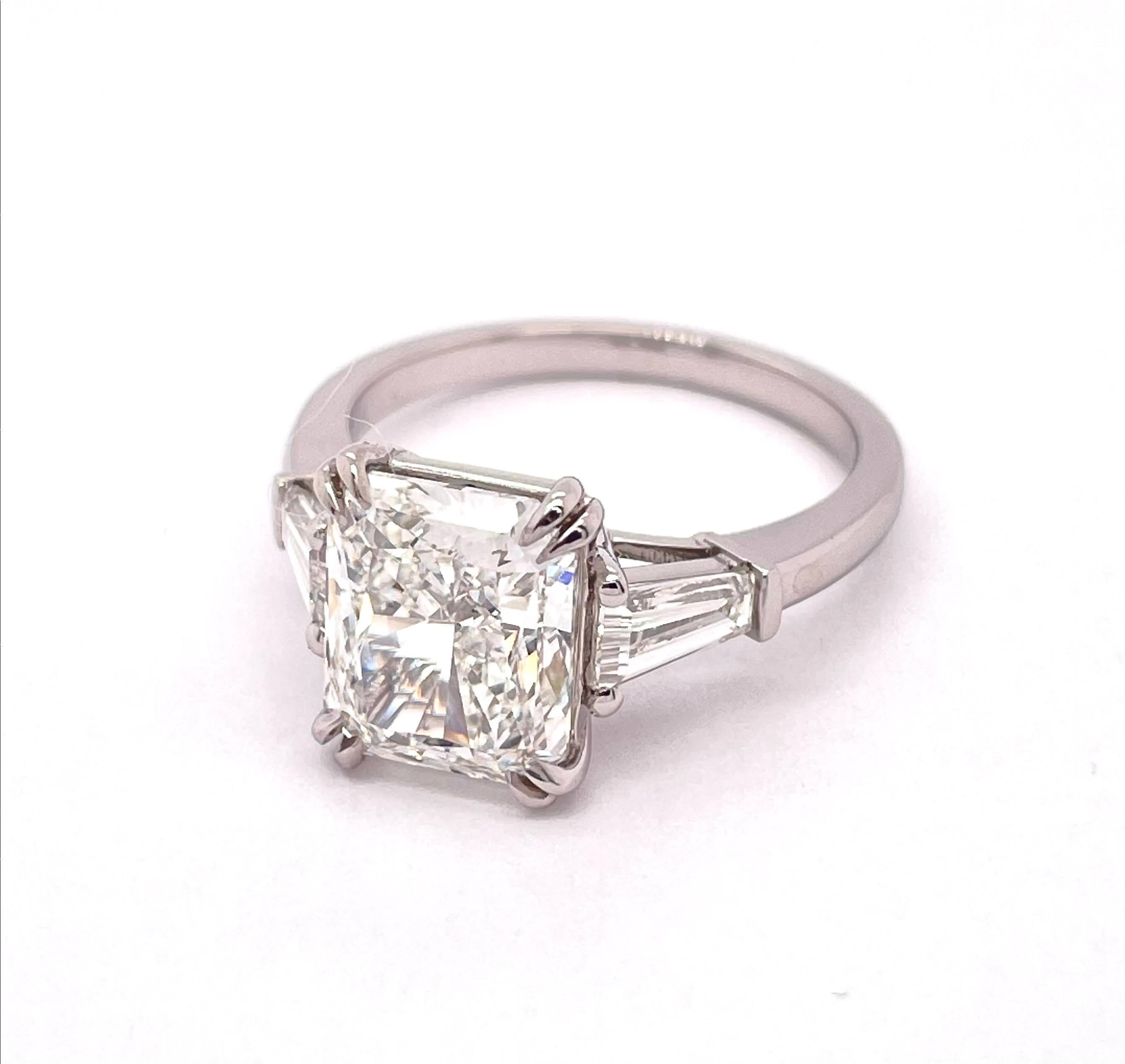 GIA Certified Radiant Shape Cut Diamond 3.54, H Color VS1 Clarity held by claw prongs with 0.73 Tapered Baguettes on each side to glide smoothly on the platinum mounting. Made to perfection with the highest quality. 
