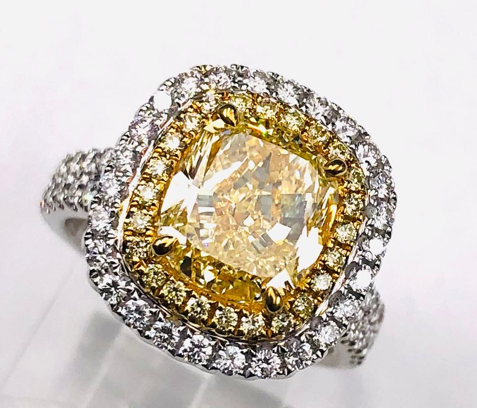This is a classic double halo ring with natural yellow diamonds on the interior halo and natural white diamonds on the outer halo. This cushion diamond is cut extremely well with only 64.1% depth -- which means that the diamond isn't cut on the deep