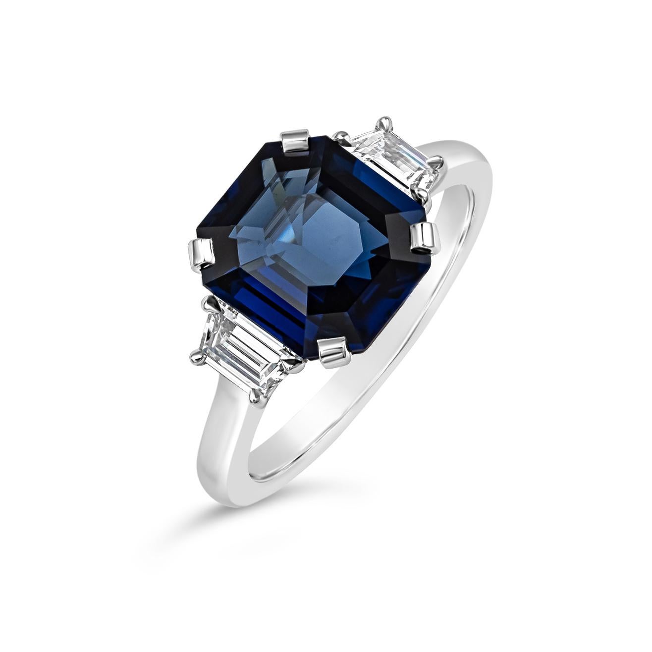 Ein klassischer und zeitloser Verlobungsring mit einem blauen Saphir im Smaragdschliff von 3,73 Karat, flankiert von zwei trapezförmigen Diamanten im Stufenschliff auf beiden Seiten. Die Diamanten wiegen insgesamt 0.40 Karat und sind ungefähr von