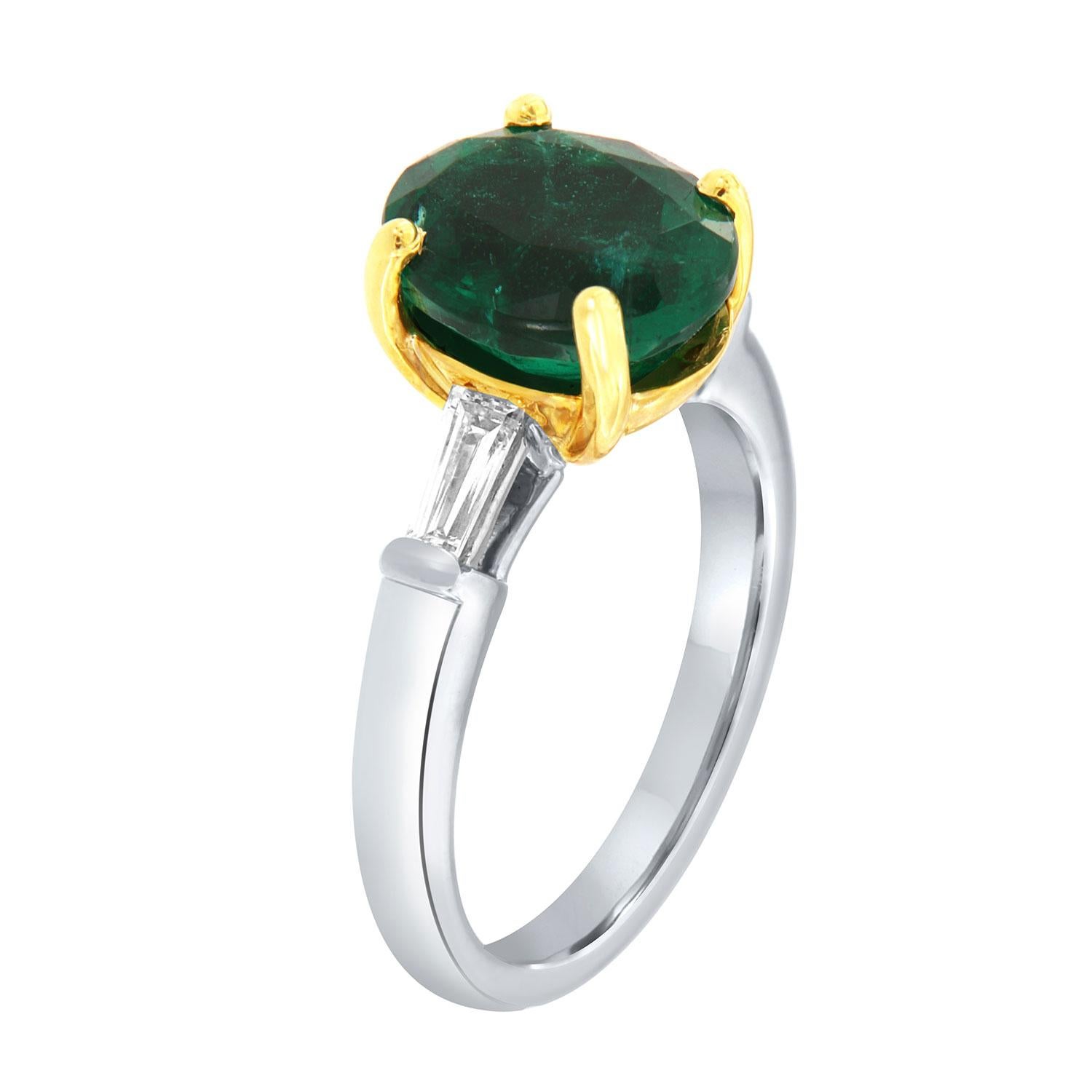 This classic Platinum and 18k Yellow Gold ring features a 3.86 Carat Oval-shaped Vibrant green Natural Emerald flanked by two(2) Baguette-shaped diamonds in a total weight of 0.36 Carat on a 2.8 mm wide band. 
This Zambian Emerald exhibits a vibrant