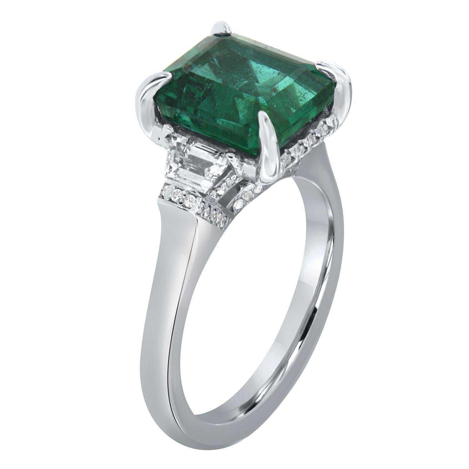 This Hand-Crafted stunning ring features 3.87- Carat  Zambian Vibrant Green Emerald GIA Certified encircled by a  hidden halo of delicate diamonds Micro-Prong set. The emerald is flanked by two perfectly matched Trapeze-shaped diamonds 0.53 carat