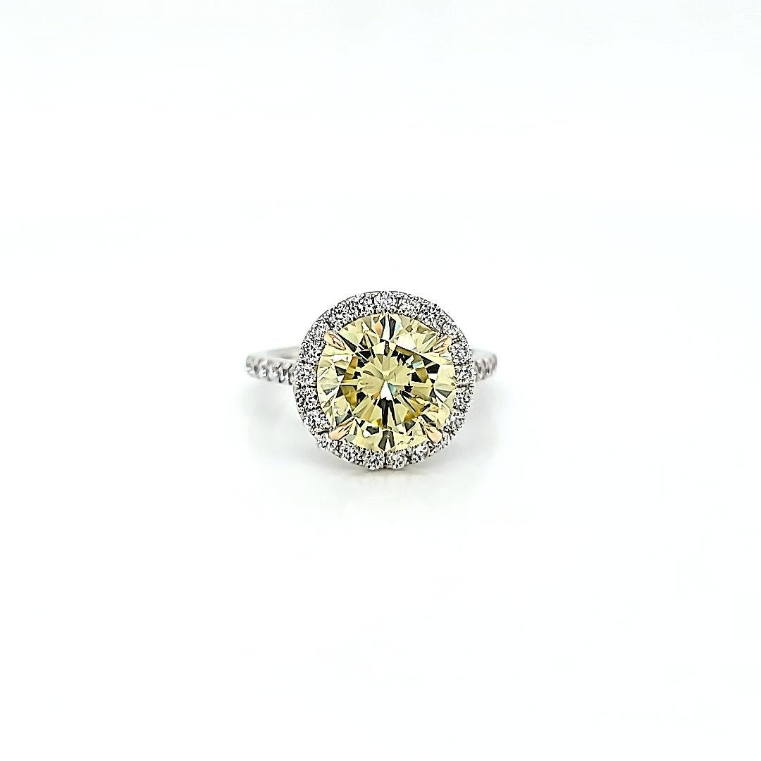 Center stone weighs 3.87 carats and is GIA certified Fancy Yellow and VVS2 clarity. Set in 18K white gold Halo mounting and diamonds on the shank. 