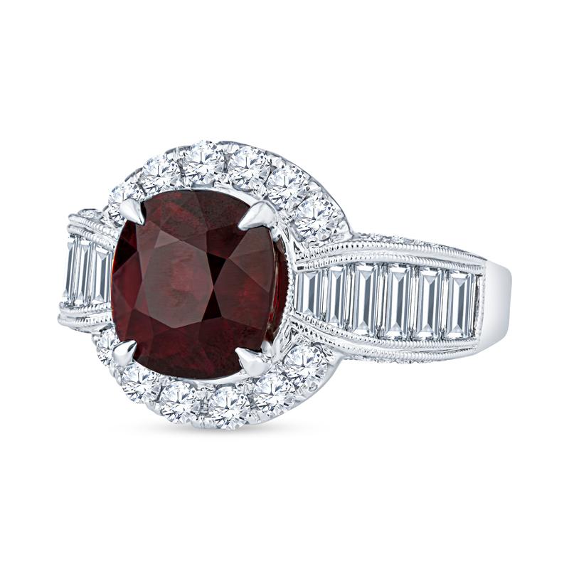 This ring features a 3.97 carat cushion cut Mozambique ruby accented by 2.31 carat total weight in round brilliant and straight baguette diamonds with milgrain details set in 18 karat white gold. This ring is a size 7 and can be resized upon