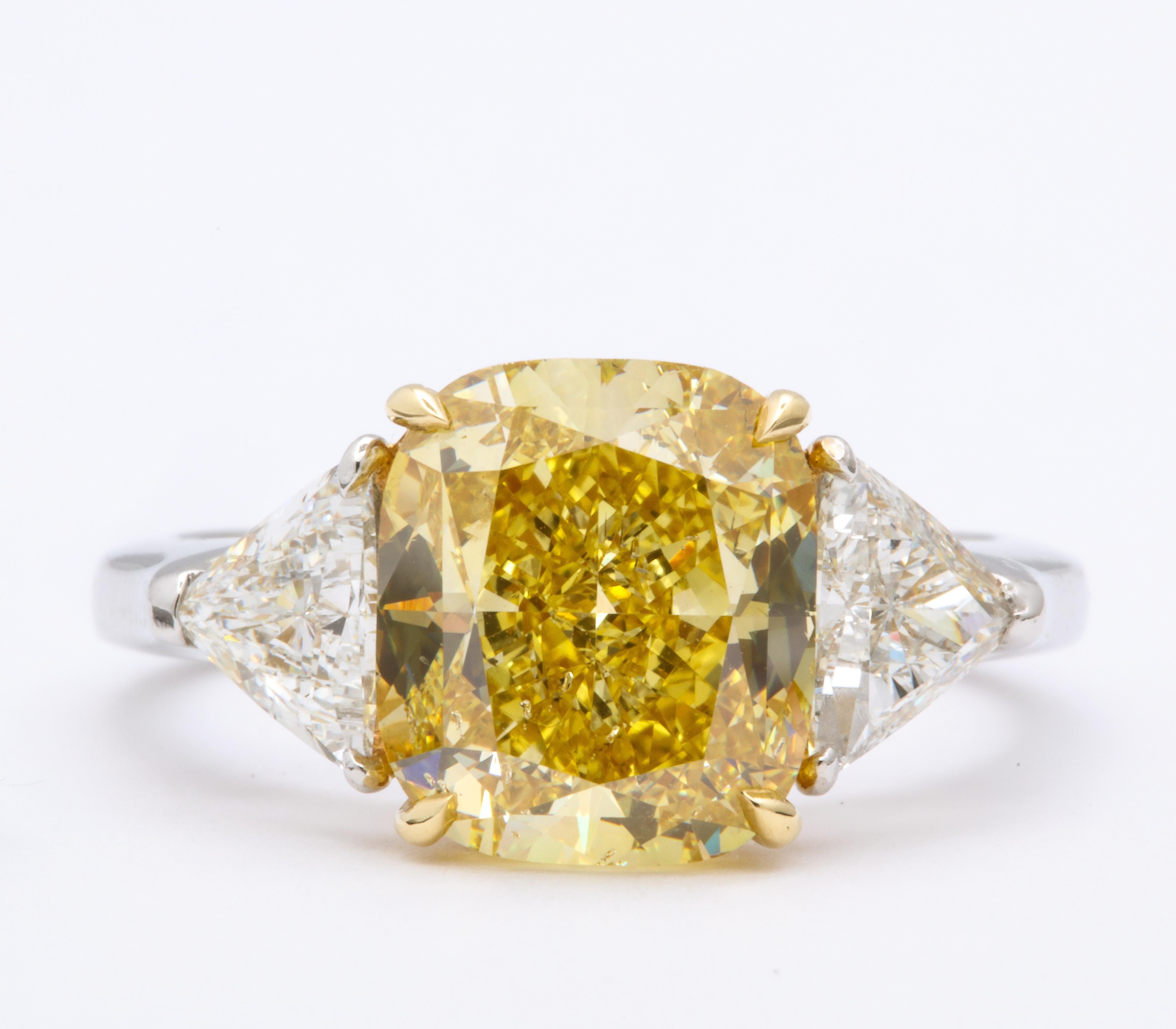 
Stunning cushion cut 4.30 carat GIA certified Fancy Intense Yellow diamond, SI2. 

Set with 1.10 carats of white trillion cut side diamonds. 

Platinum and 18k yellow

Currently a size 6, this ring can easily be sized. 

Pictures do not do this