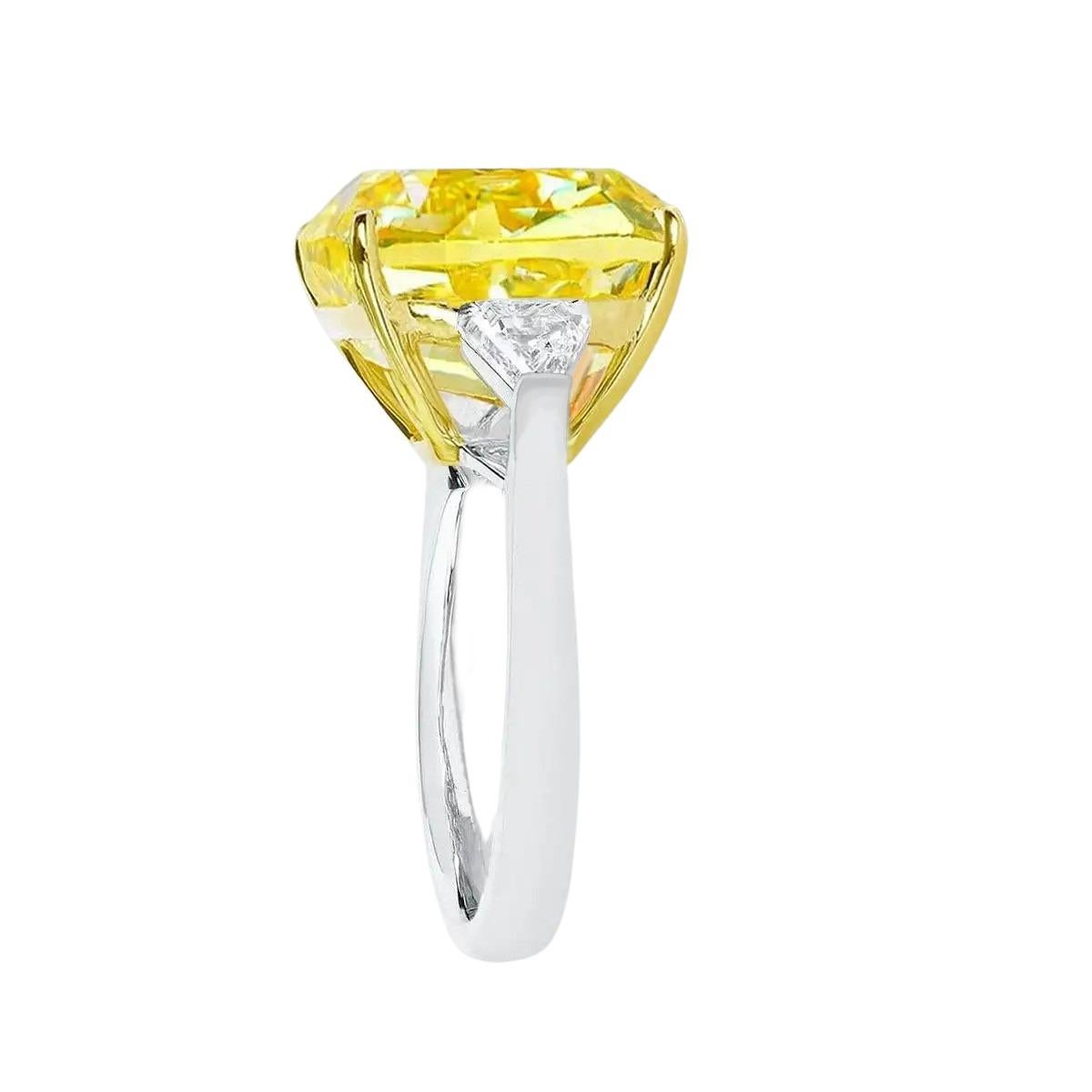 Exquisite solitaire fancy  yellow cushion cut diamond with two sidetrillion cut diamonds and set in solid 18 carats yellow gold and 18 carats white gold. The main stone offers an eye clean appearance, fantastic sparkle, and a unique and glamorous