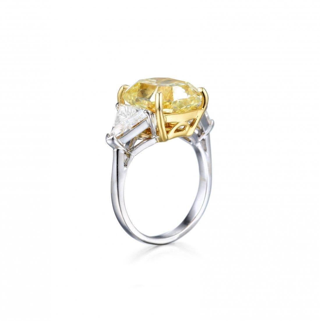 GIA Certified 4 carat Fancy Yellow Cushion Diamond Ring, adorned with exquisite trillion side diamonds, all delicately set in a combination of platinum and 18k yellow gold. This ring is a testament to unparalleled craftsmanship and luxury. The