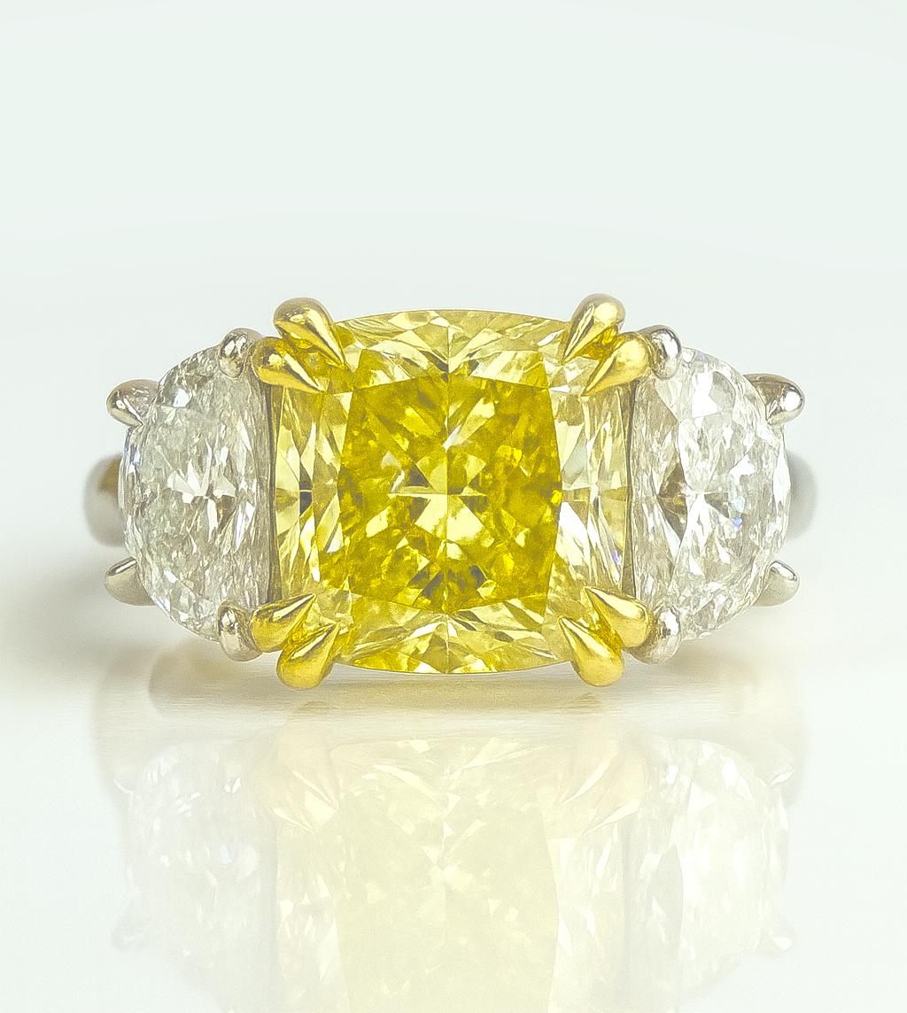 Magnifique bague à trois pierres ornée d'un vibrant diamant jaune Fancy Cushion Modified Brilliant de 4 carats certifié par le GIA, sans défaut interne, monté dans une élégante combinaison d'or jaune 18 carats et de platine.

Le superbe diamant