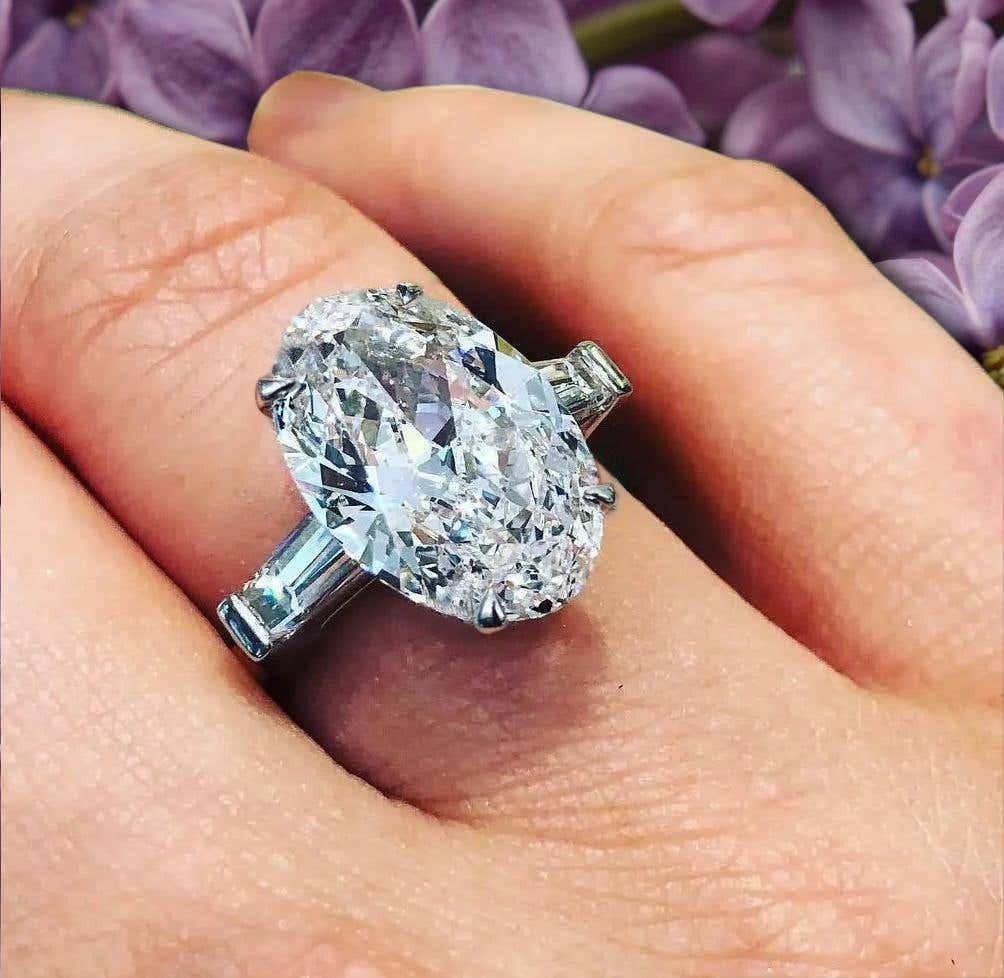 Presenting an exquisite diamond ring featuring a GIA certified 4-carat oval diamond, whose visual impact surpasses its carat weight, resembling the brilliance of a 5-carat diamond due to its elongated proportions. The diamond showcases excellent