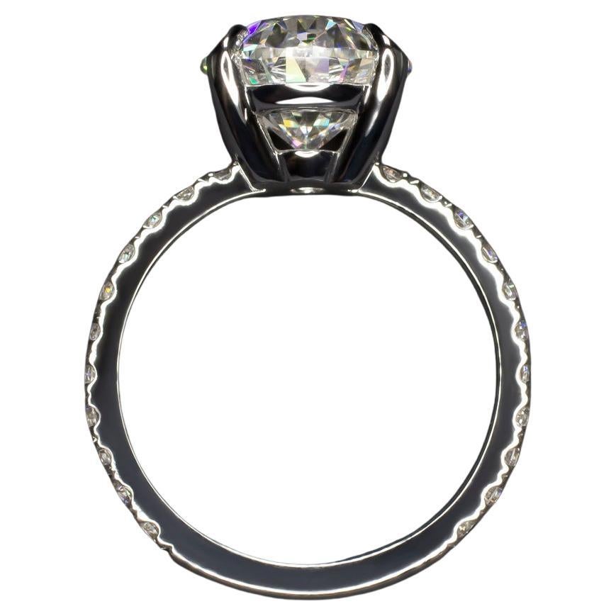 This elegant 4.02 carat oval cut diamond ring is a stunning blend of beauty and craftsmanship, designed to captivate and inspire. Set in 18K white gold, the ring is further enhanced by a pavé diamond band, adding a touch of sparkle and
