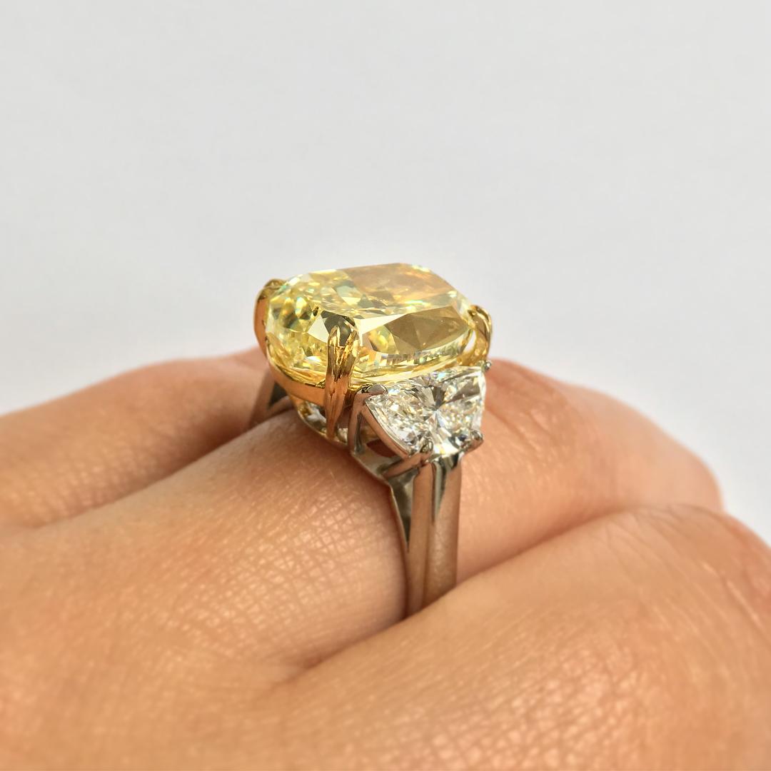A magnificent three stone diamond ring composed by a 4 carat Oval cut diamond in clarity and Fancy Yellow Color. The side half moon cut diamonds at each side weight approximately 1 carat and are F in color and VS in clarity. 

The total weight in