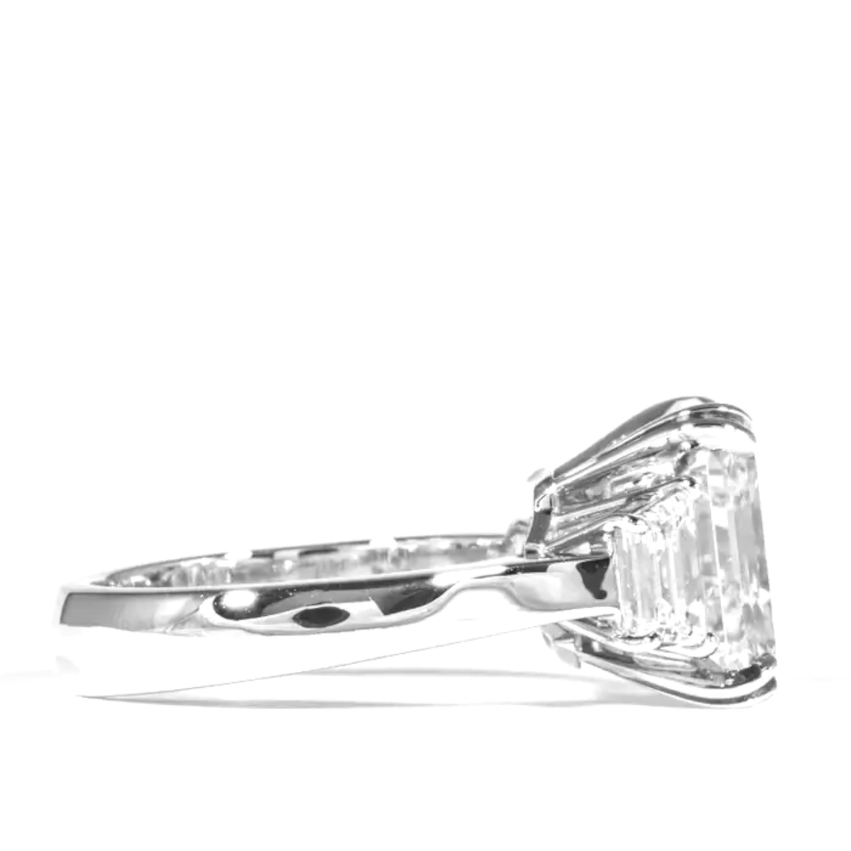 This exquisite ring by Cecile Blake is crafted in platinum and features a breathtaking 4 carat assche cut diamond, certified by GIA. The vibrant center stone is accented by two tapered baguette diamonds, adding a sophisticated touch to this elegant