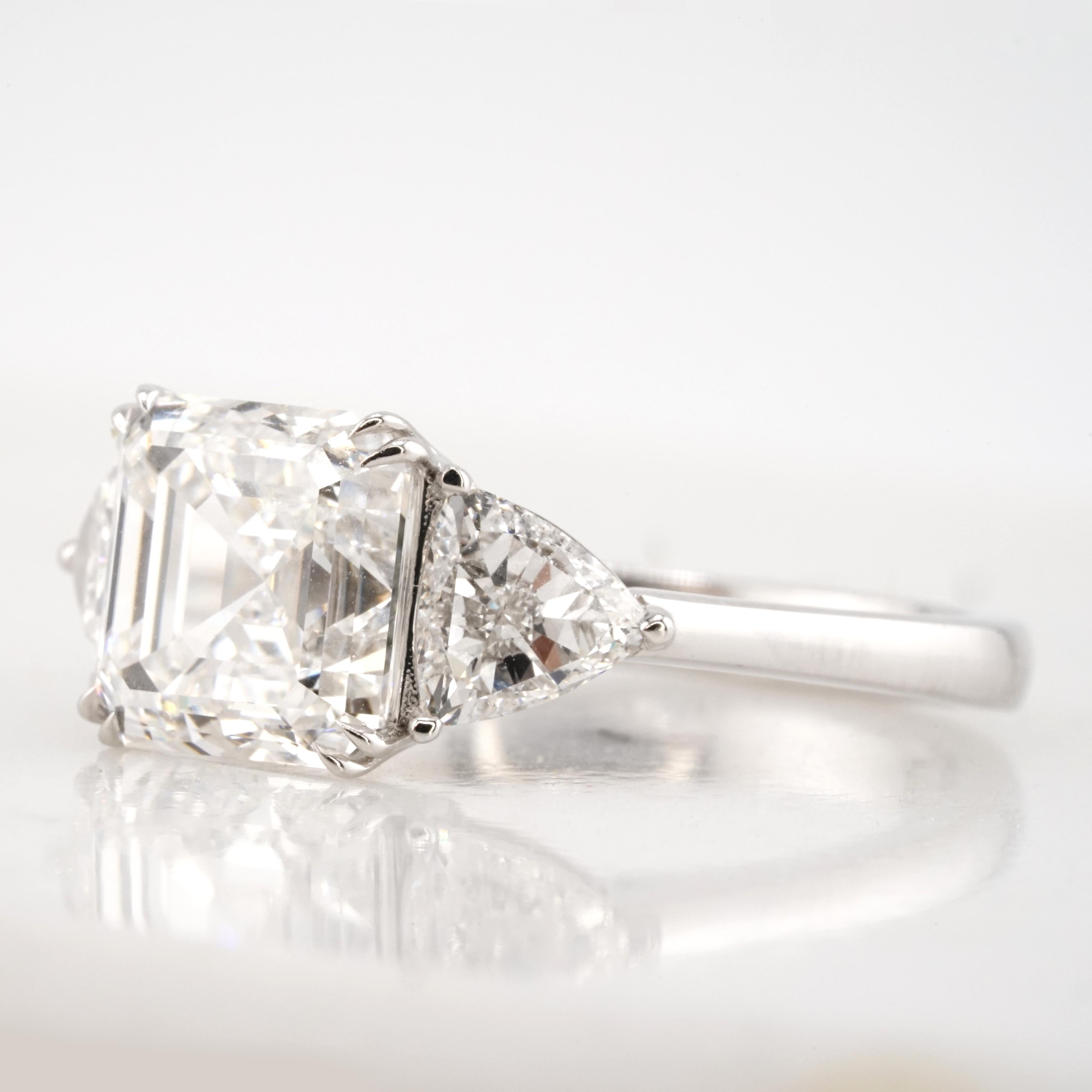 A timeless and elegant three-stone engagement ring featuring a stunning 4 carat Asscher cut diamond, certified by GIA as G color and VS1 clarity. The diamond is beautifully eye-clean, with excellent polish and excellent symmetry.  Faint