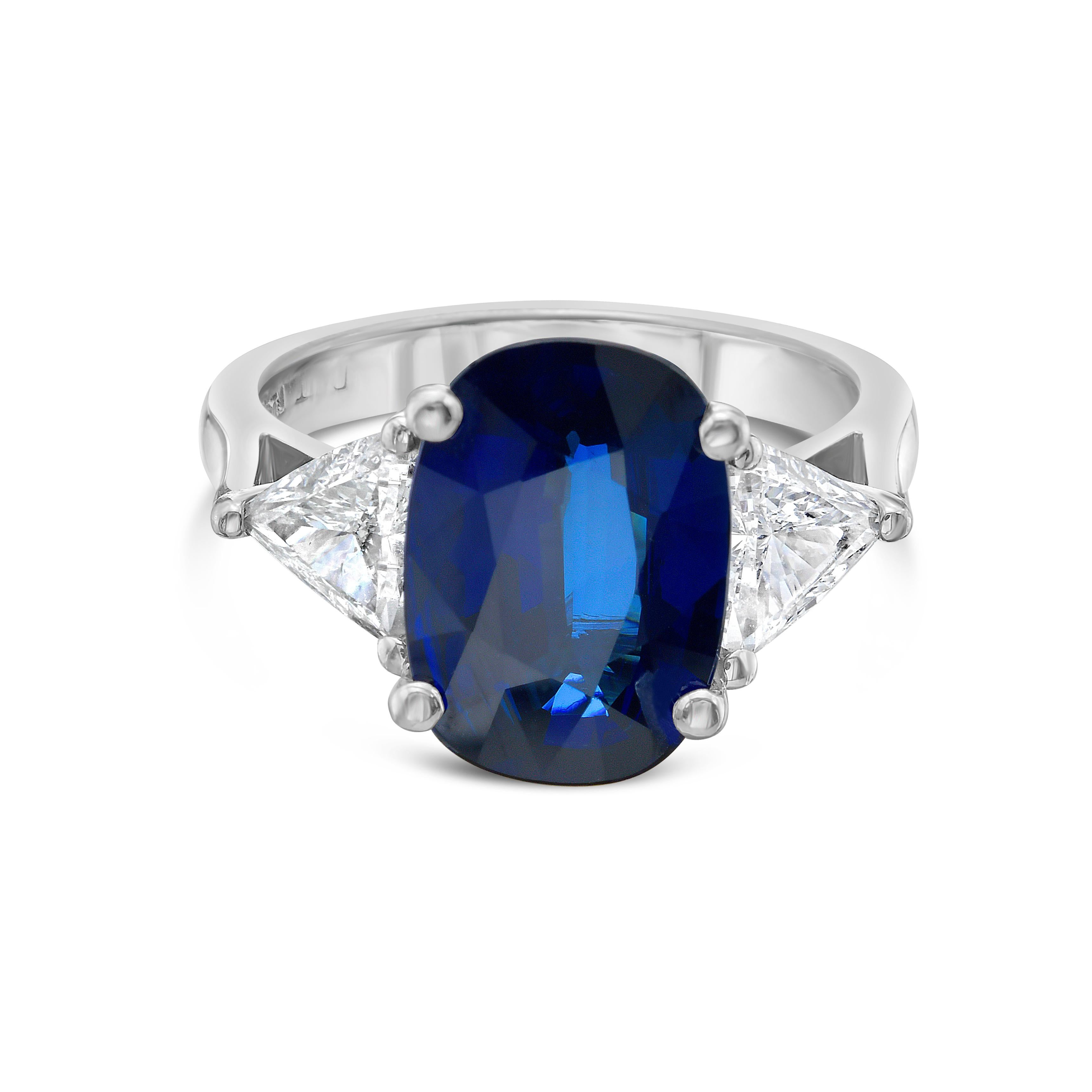This beautiful cocktail ring showcases a stunning GIA Certified 4.01 carat Cushion Sapphire flanked by two Trillion Cut Diamonds (0.85 carats) set in Platinum. Ring size is 6.