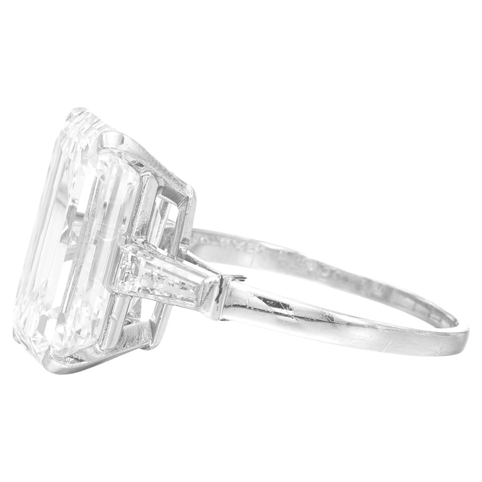 This exquisite three-stone ring features a 4.01-carat emerald-cut diamond as its centerpiece, offering timeless beauty and elegance. 

Certified by GIA, the diamond is graded F in color, presenting a bright and nearly colorless brilliance. 
With a