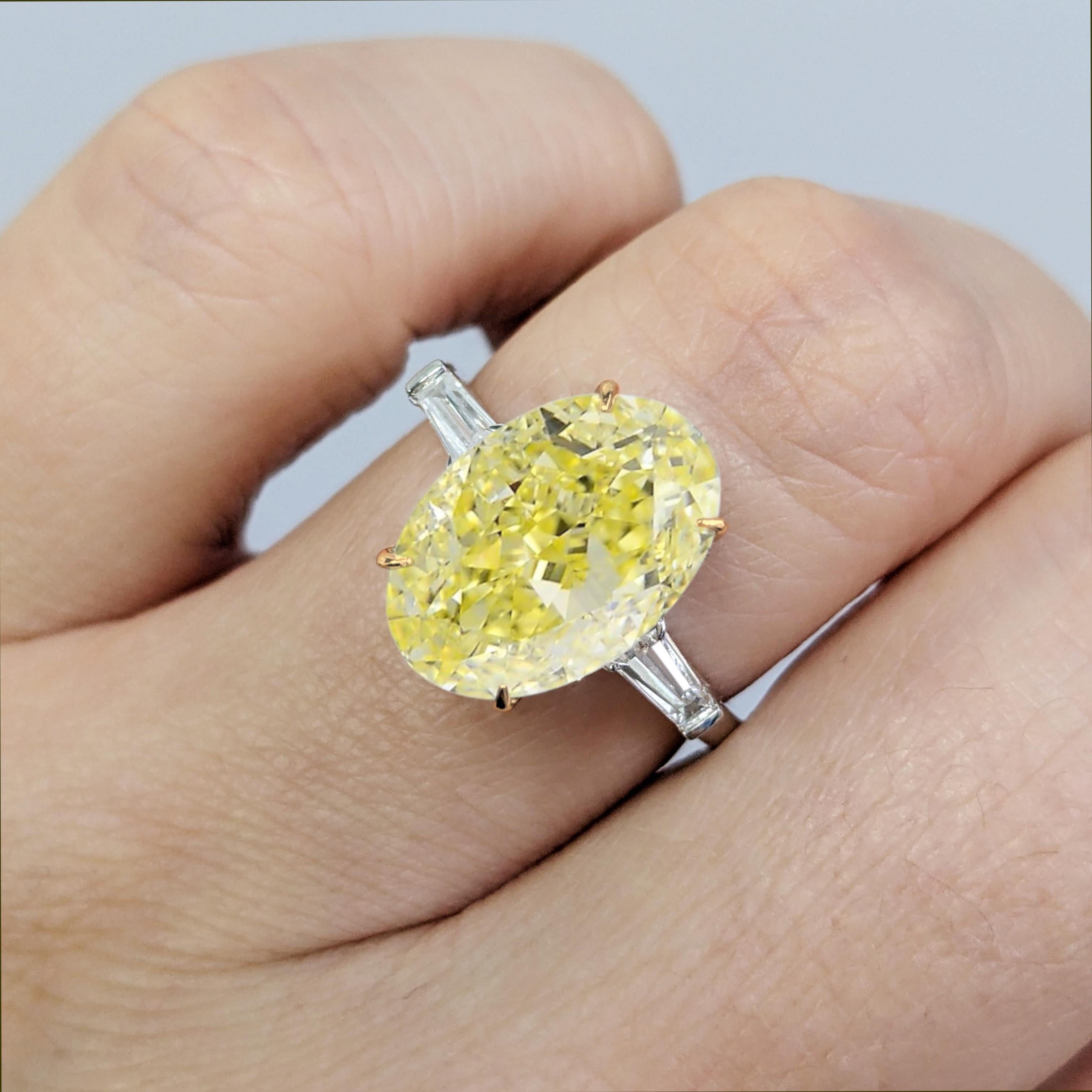 An exquisite and rare GIA-certified 4.02-carat Fancy Yellow oval modified brilliant-cut diamond takes center stage in this stunning platinum ring. The diamond, boasting VS1 clarity, showcases a vibrant and evenly distributed yellow hue that radiates