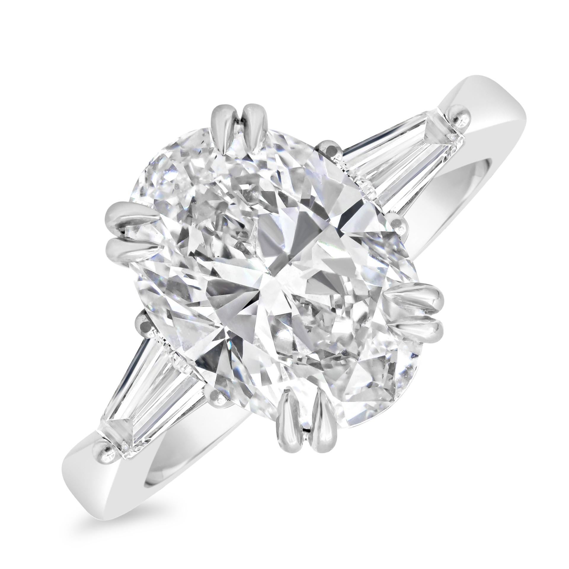 Featuring a GIA Certified 4.01 carats oval cut diamond, G Color and  VS2 in Clarity. Flanking the center are two tapered baguette diamonds weighing 0.54 carats total. Set in a double prong setting. Made with polished Platinum. Size 6 US and