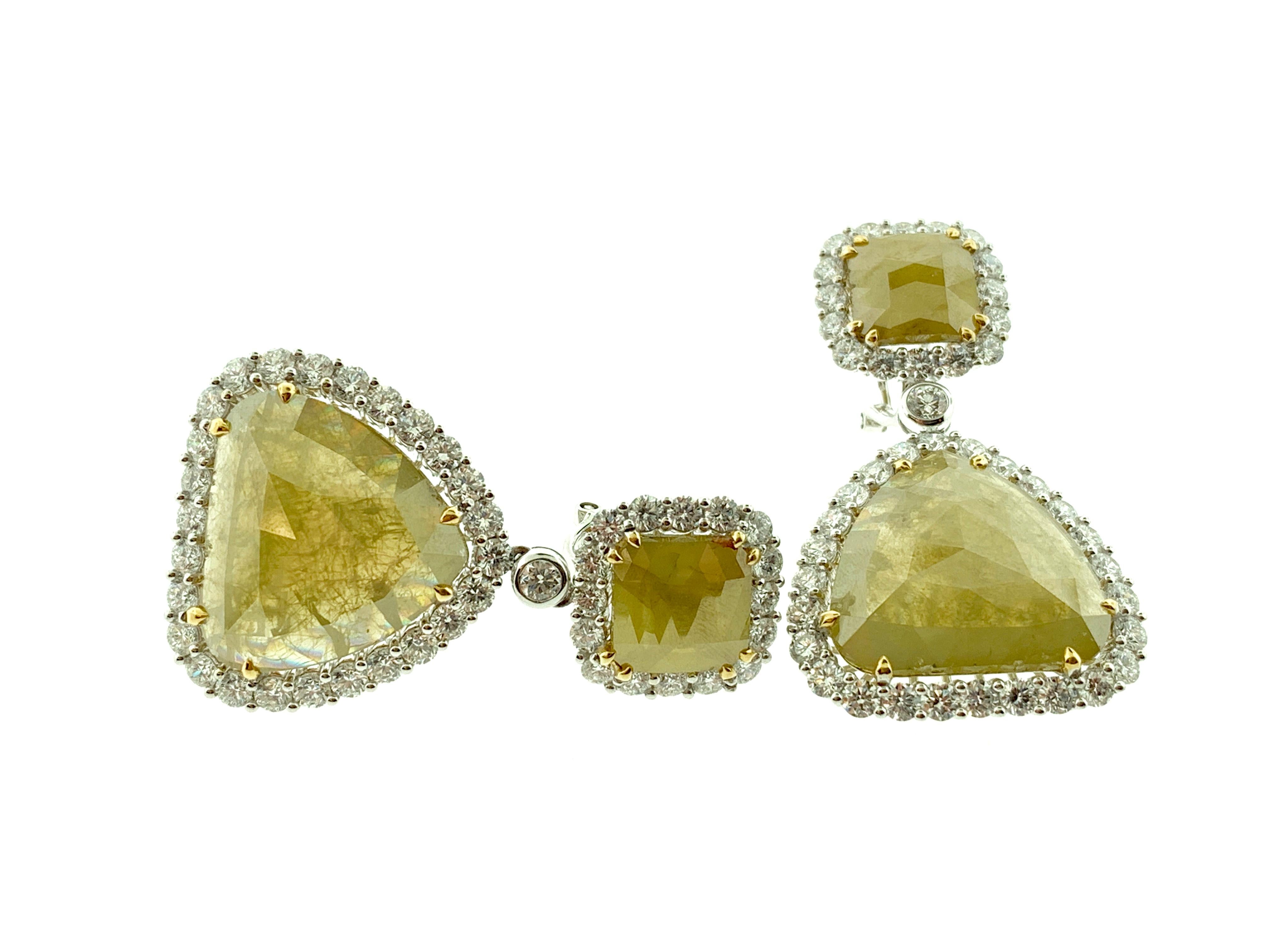 These stunning earrings feature 2 Rose Cut Natural (unheated) Fancy Yellow Diamonds, total of 32.52 carats, encircled in a single halo of round brilliant Diamonds. 

They are hanging from Emerald Cut Natural Fancy Yellow Diamonds, total of 7.66