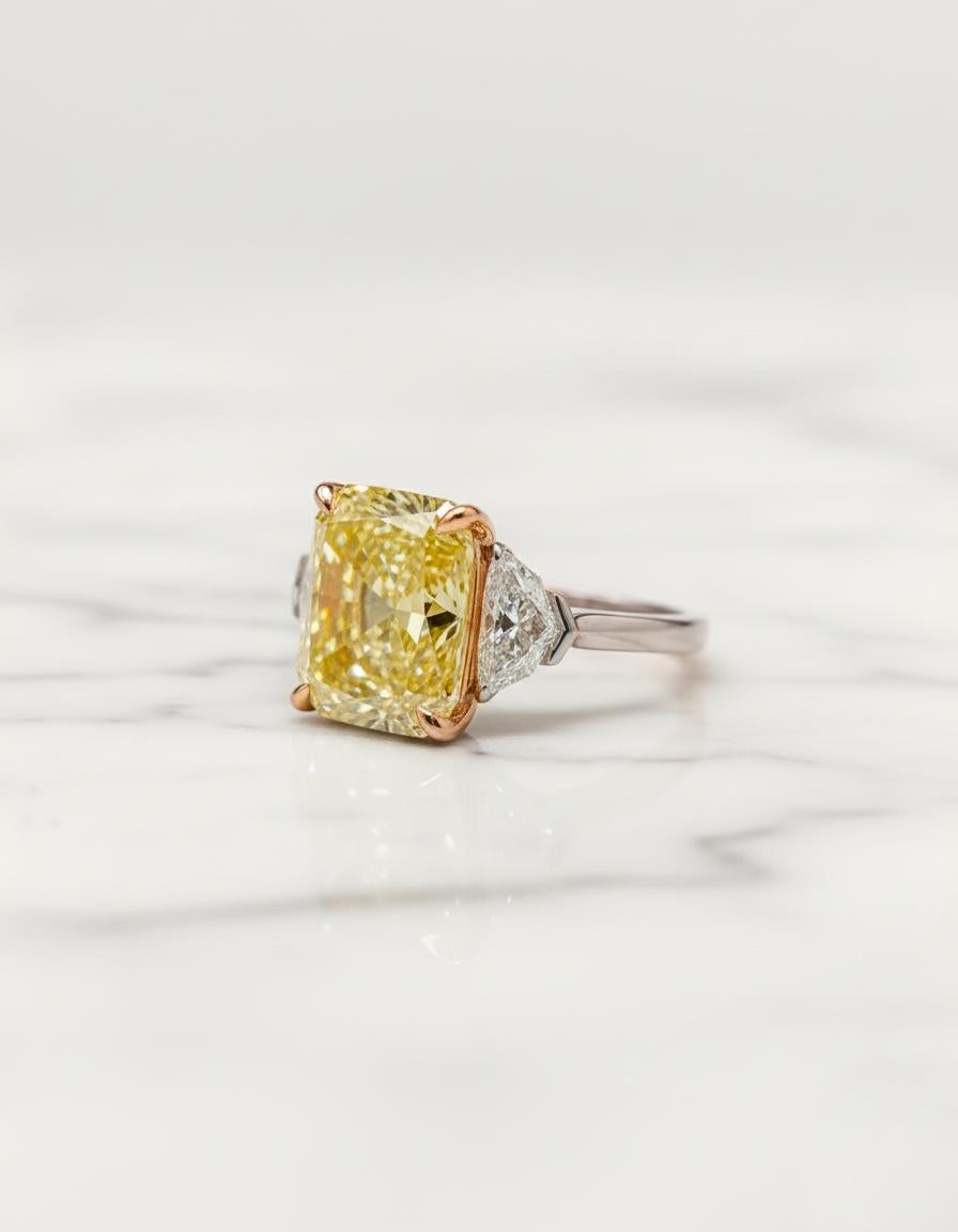 Questo anello eccezionale mette in mostra un magnifico diamante giallo intenso Fancy da 4,02 carati certificato GIA, tagliato a forma di Brilliante Modificato Rettangolare con taglio ad angolo. La pietra centrale mostra una tonalità gialla ricca e