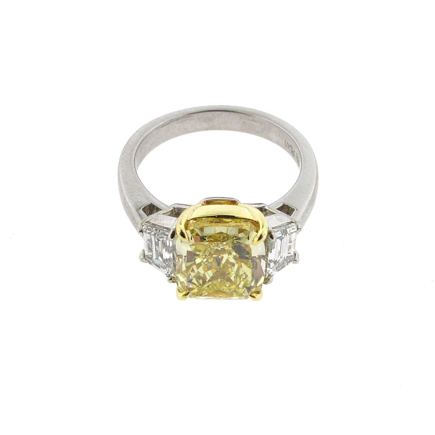 Wow!! This is a super strong Fancy Yellow cushion cut diamond ring. The center stone is 4.02 carats and looks amazing. The center stone is set between 2 trapezoid diamonds of extremely white clarity and super high clarity. The ring is platinum while