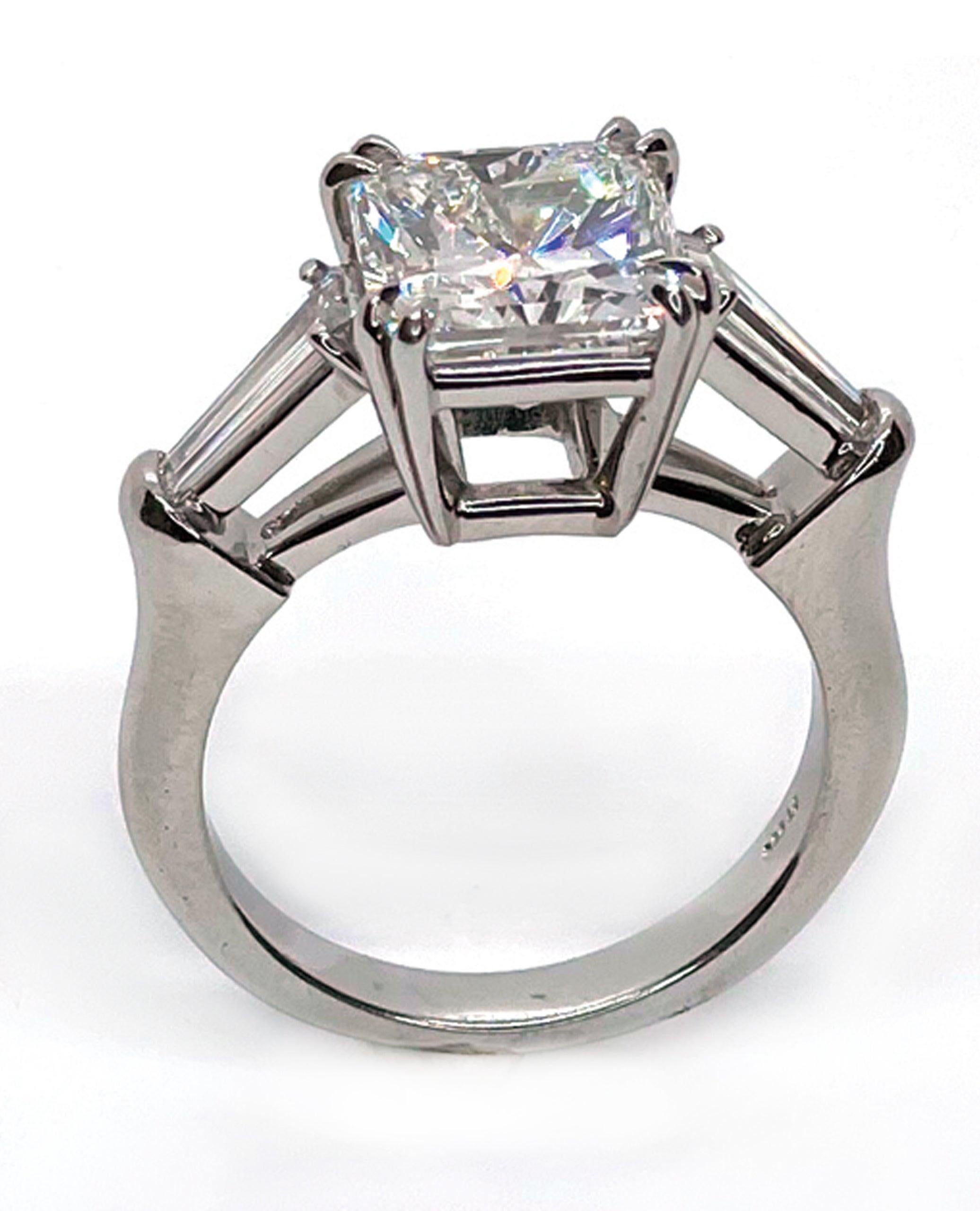 Platinum hand made three stone ring with two tapered baguette diamonds totaling 0.56 carats (G color / VS clarity) and one center GIA certified radiant cut diamond totaling 4.02 carats (I color / VS1 clarity).

-Size 7
-GIA Report No.: 13778088