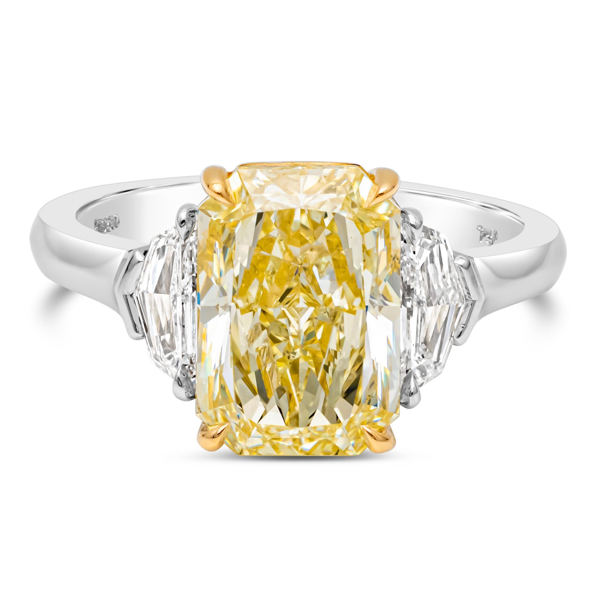 This gorgeous three stone engagement ring features a 4.02 carats radiant cut fancy yellow diamond certified by GIA  as Y-Z color, SI1 in clarity and set in a classic four prong basket setting. Flanked by diamonds on each side weighing 0.51 carats