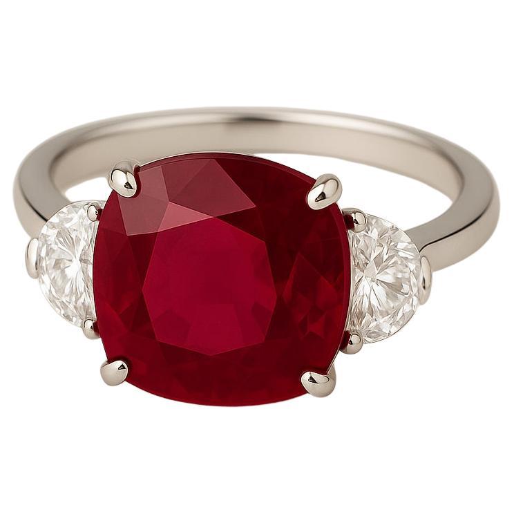 This exceptional three-stone ring showcases a striking 4.03 carat cushion-cut ruby of Burmese origin, certified by GIA. The ruby displays a rich, vivid red hue with excellent transparency, further enhanced by the expert cut that brings out its
