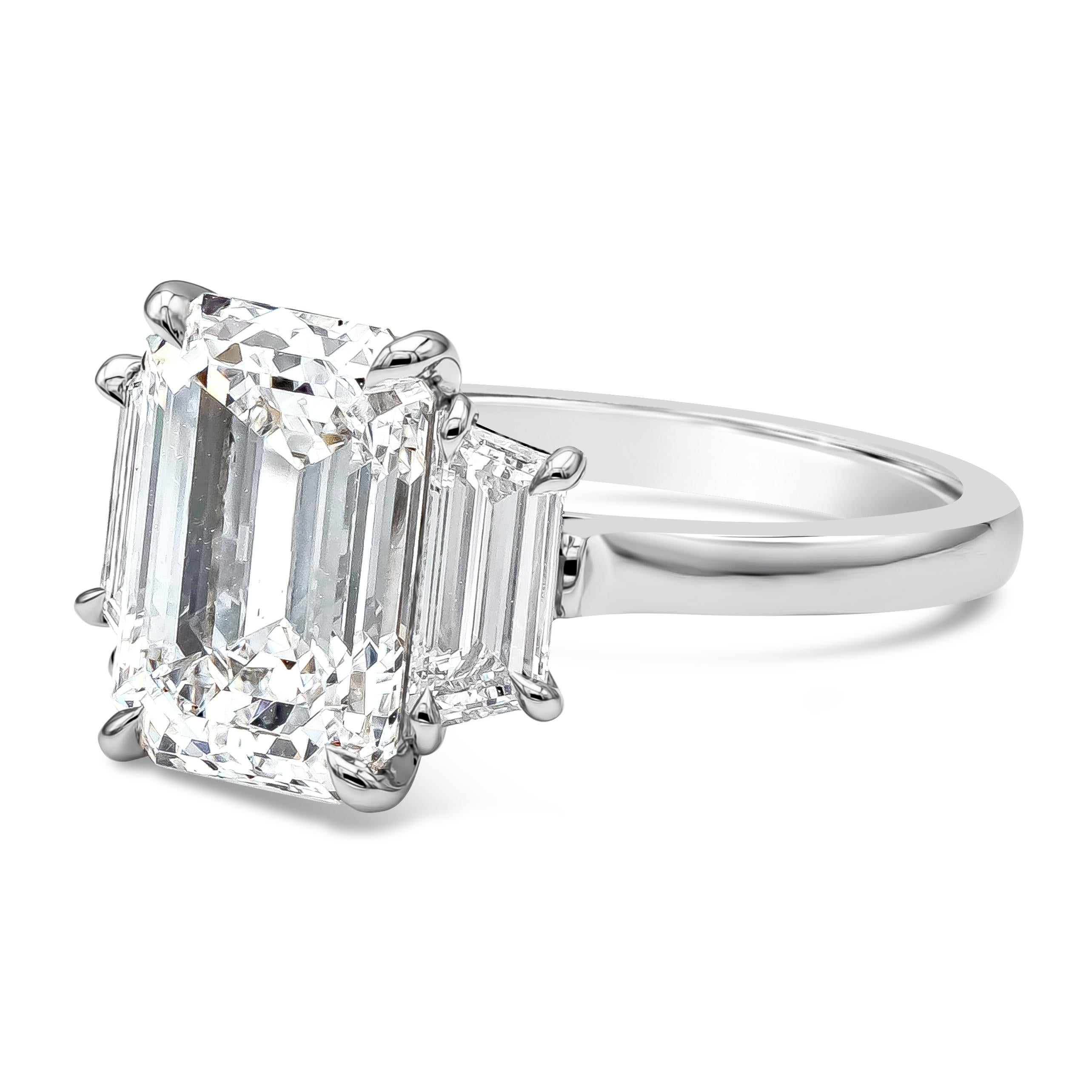 A classic and timeless three-stone engagement ring style showcasing a 4.07 carats emerald cut diamond certified by GIA as D color, SI1 in clarity, flanked by step-cut trapezoid diamonds on either side. Accent diamonds weigh 0.84 carats total and