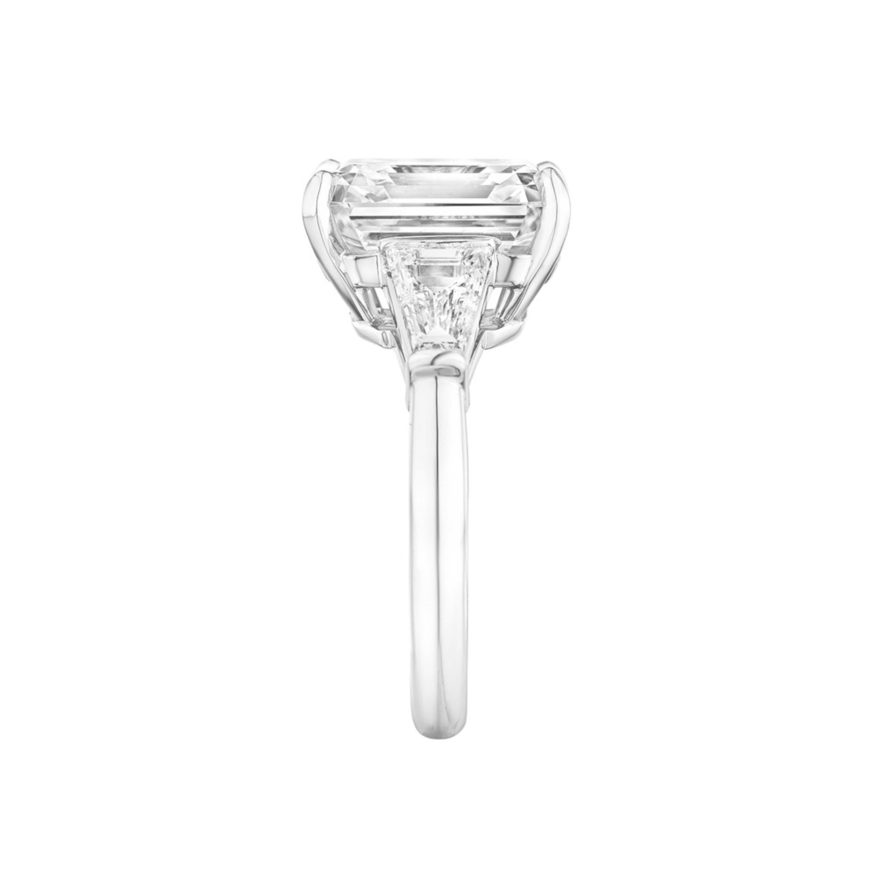 This refined engagement ring showcases a 4.03 carat emerald-cut diamond, GIA certified for its exceptional quality and timeless appeal. The step cut facets of the center stone create a striking hall-of-mirrors effect, revealing elegant flashes of